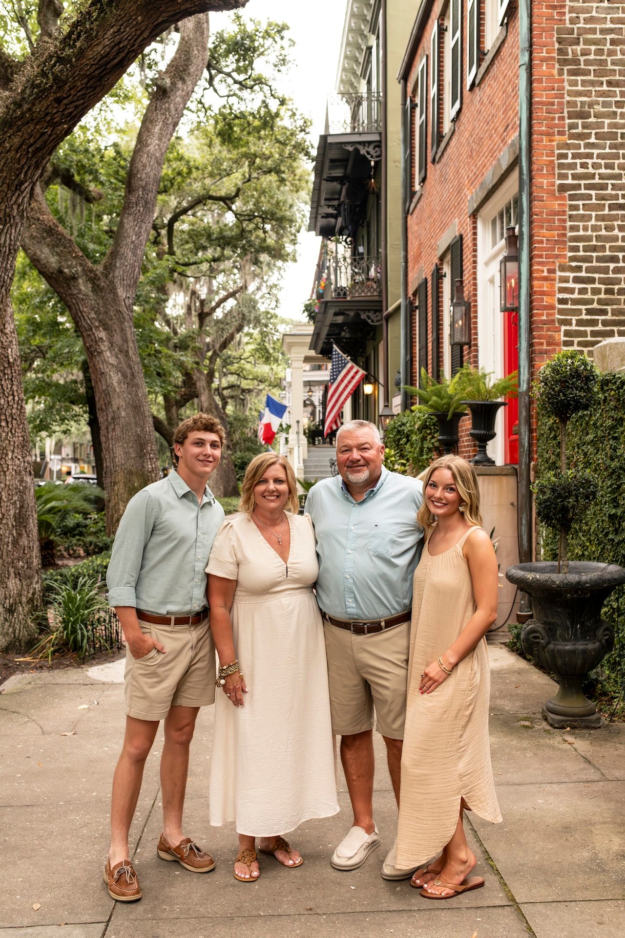 A family stands together on a historic brick-lined street in Savannah for a family portrait.