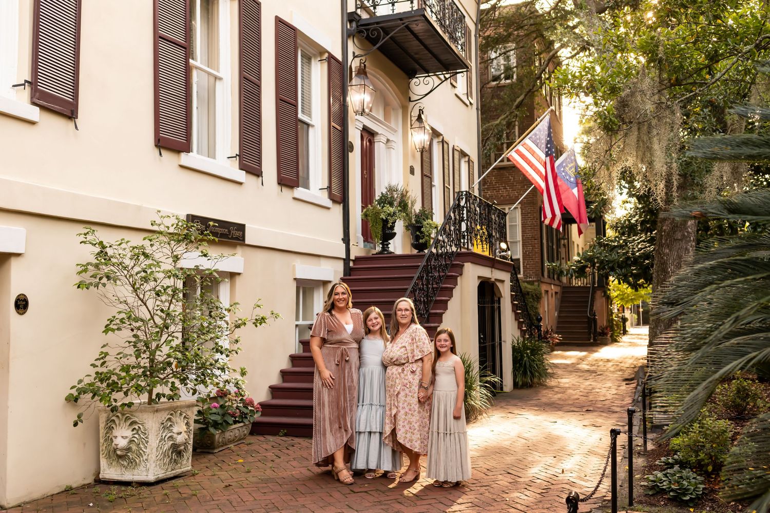 A group poses with historic brownstone steps with flags displayed in Savannah, Georgia.