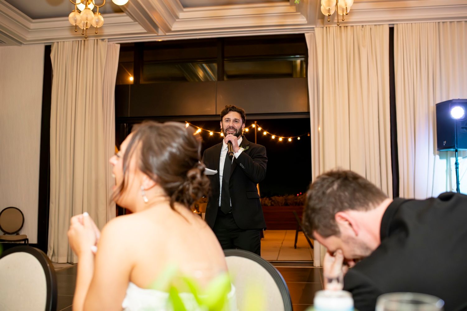Wedding guests dance and celebrate on an elegant ballroom dance floor under crystal chandeliers.