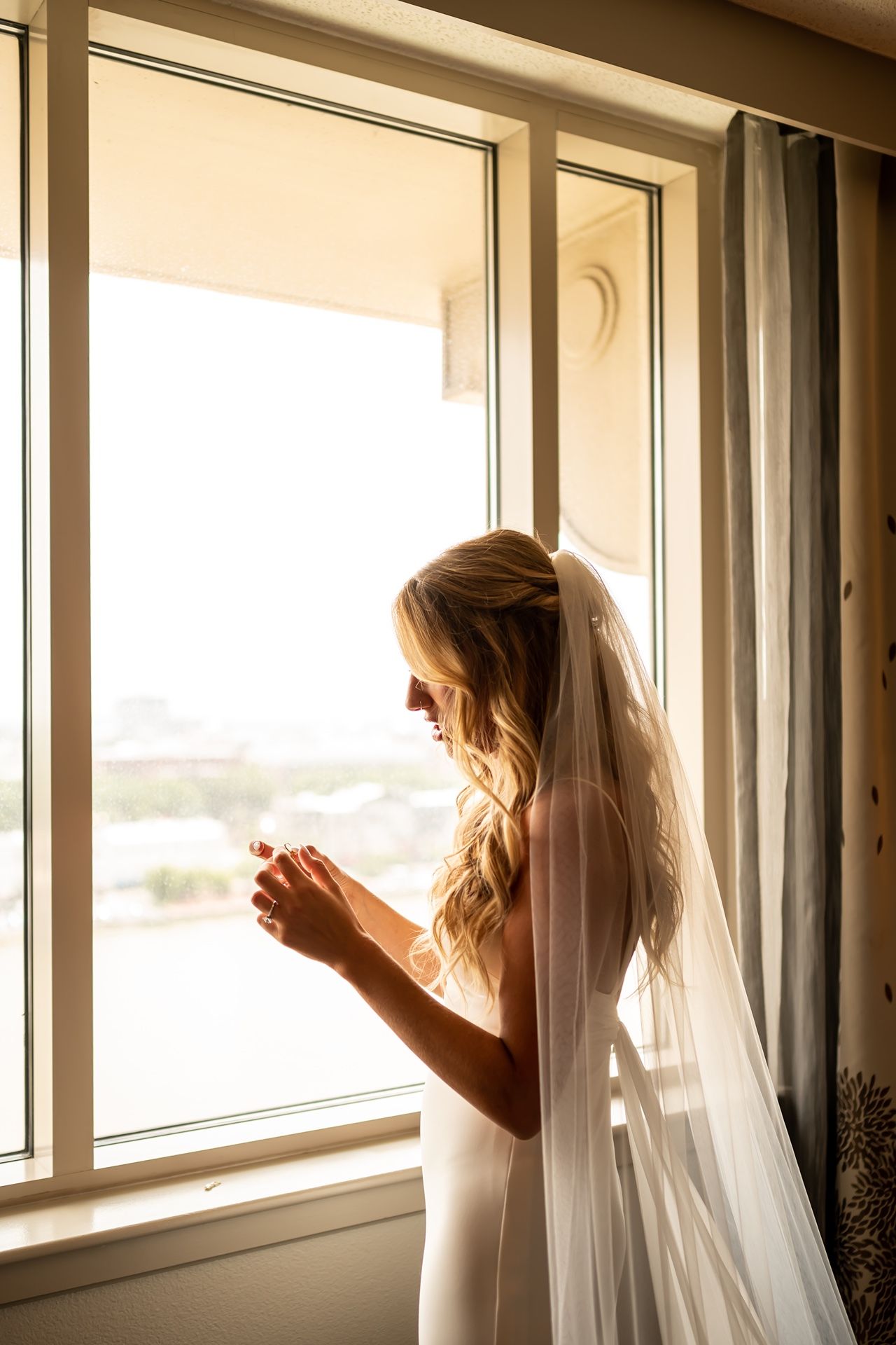 A bride in a white veil peers through a window in a sequence of three similar poses creating a dreamy effect.