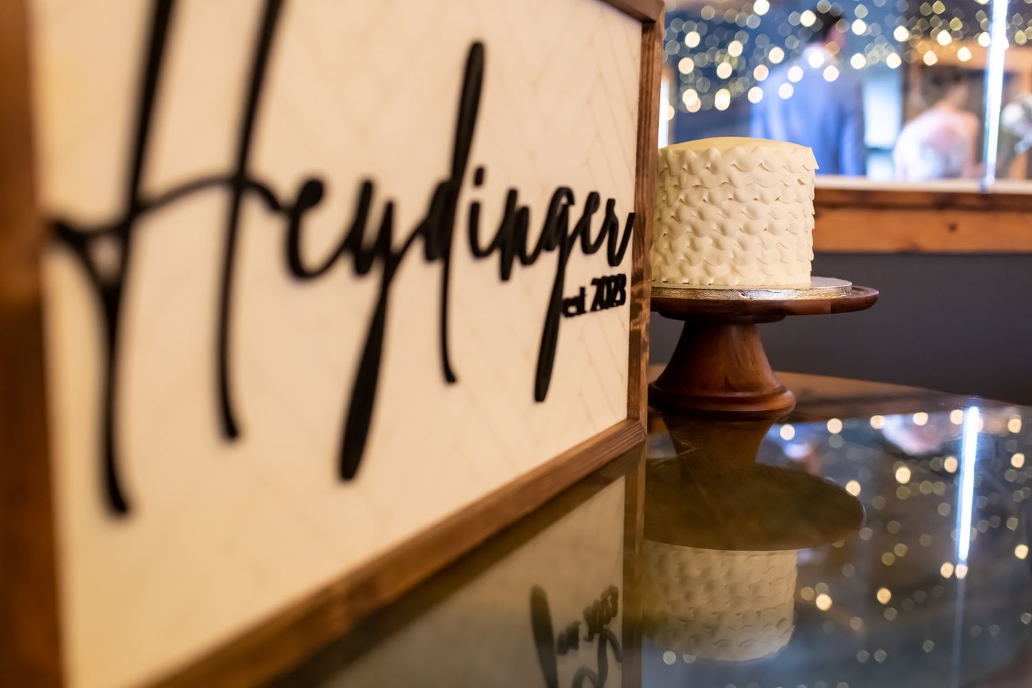 A stylish bar interior with a black script logo and elegant straw hat displayed on a reflective surface.