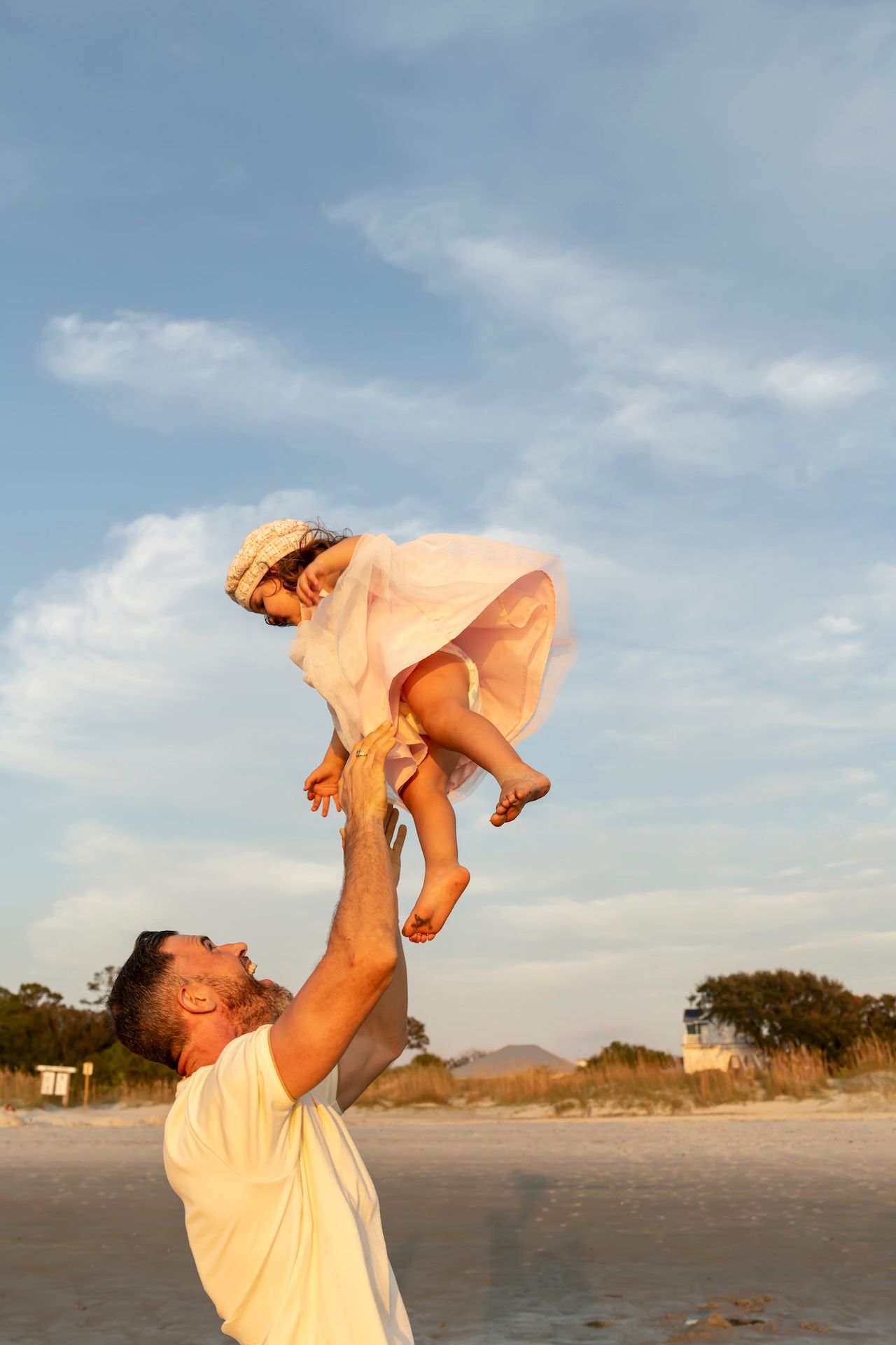 A series of joyful moments captured on a beach during golden hour with wispy clouds in the sky.