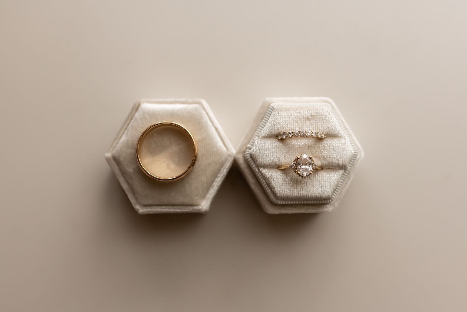 Two decorative white marble hexagonal containers with gold accents and tapered lids displayed on a beige surface.