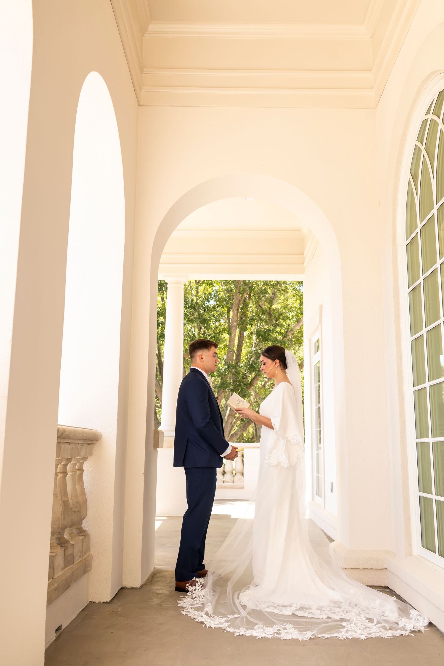 Wedding couple in elegant white colonnade with arched windows at Savannah Country Club.