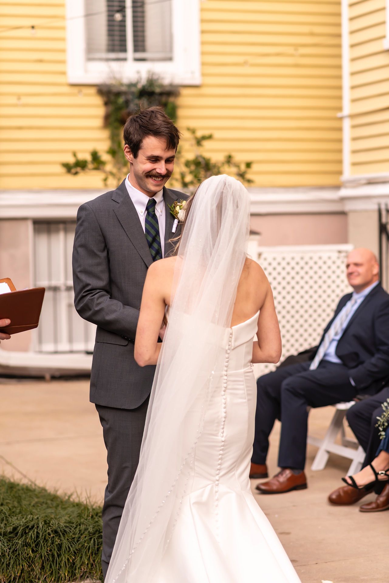 Wedding couple share a playful moment on church steps during outdoor ceremony.