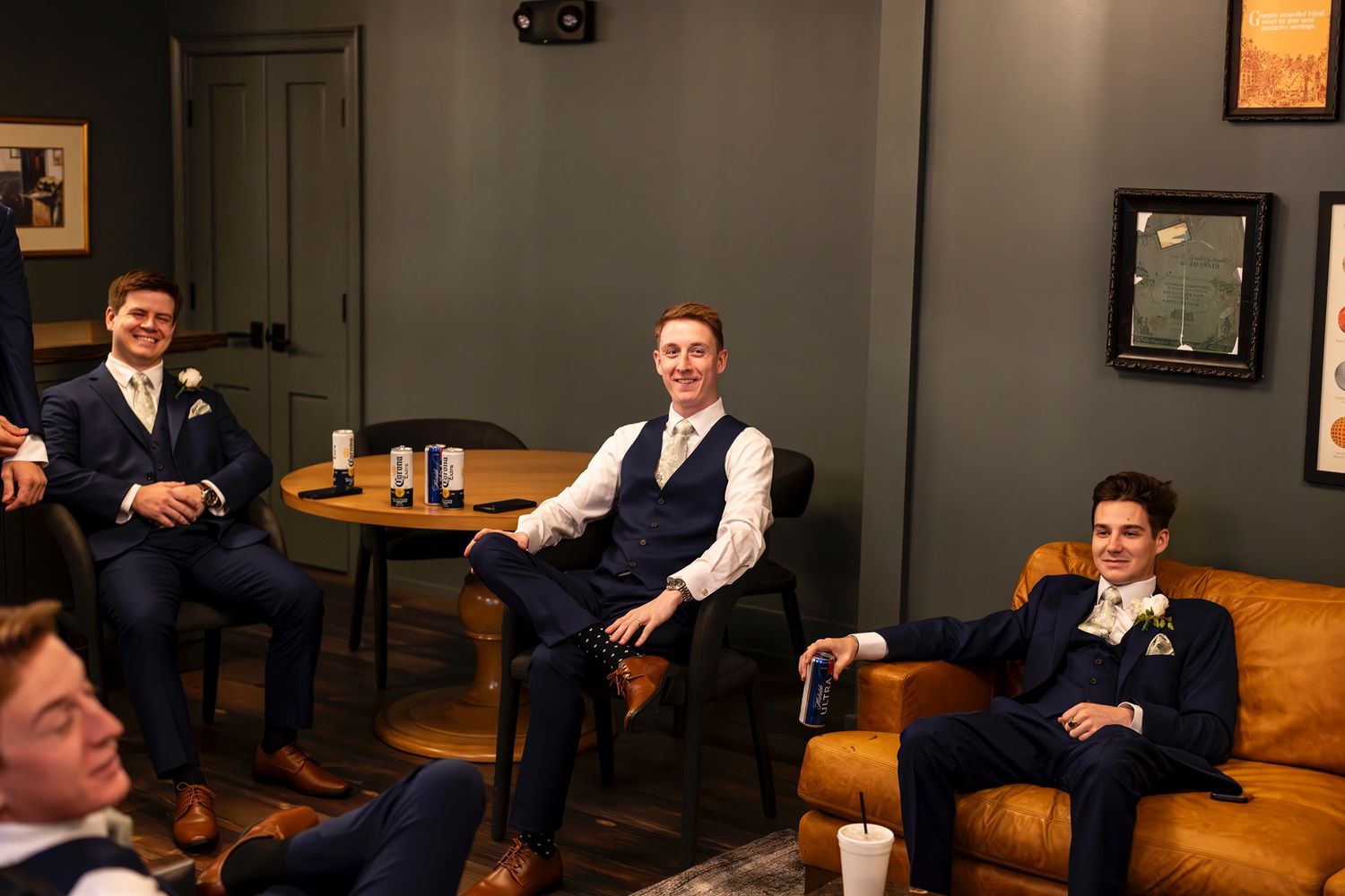 Group relaxing in a dimly lit lounge with leather furniture during formal event.