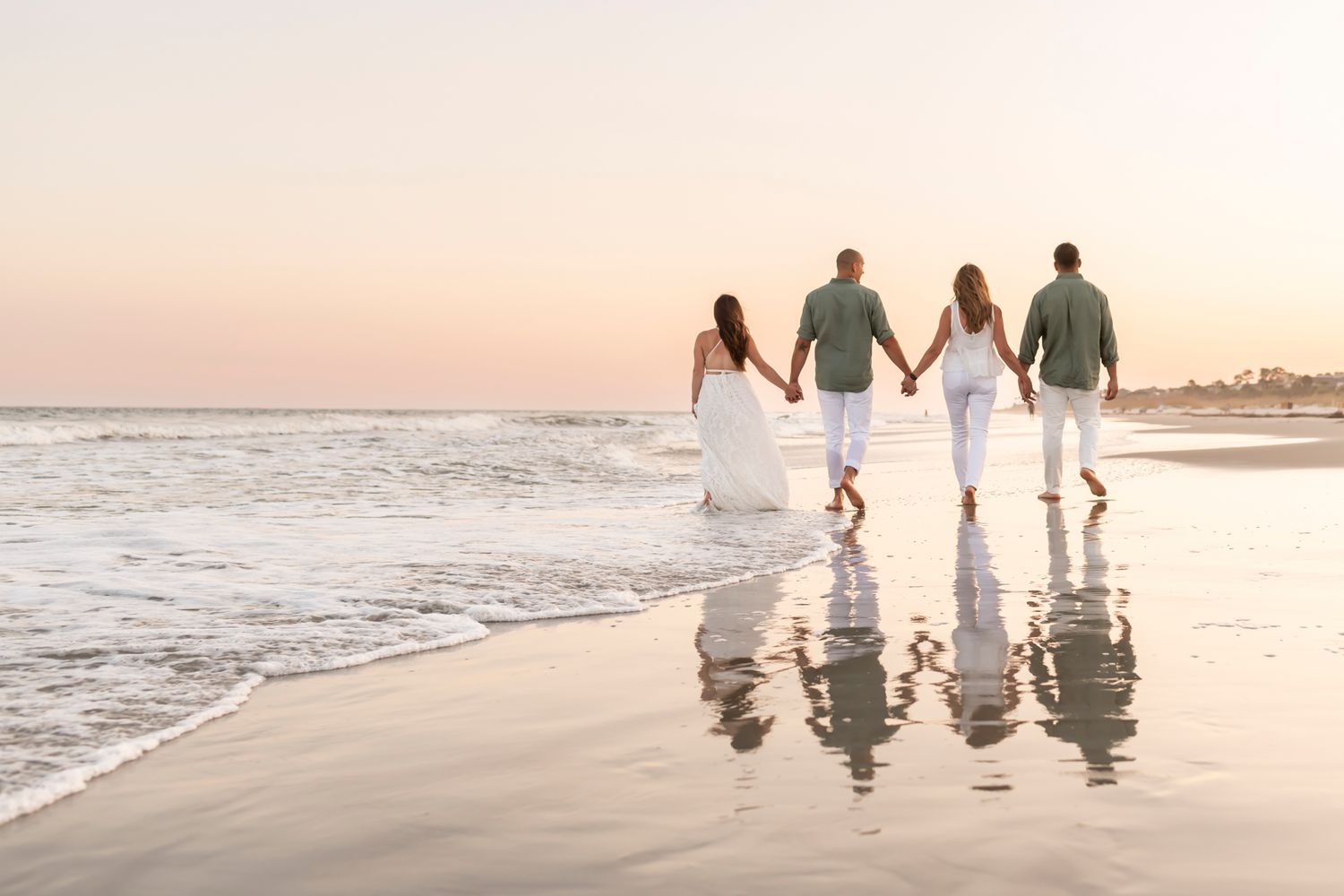 Family of four walking along Hilton Head beach at golden hour.