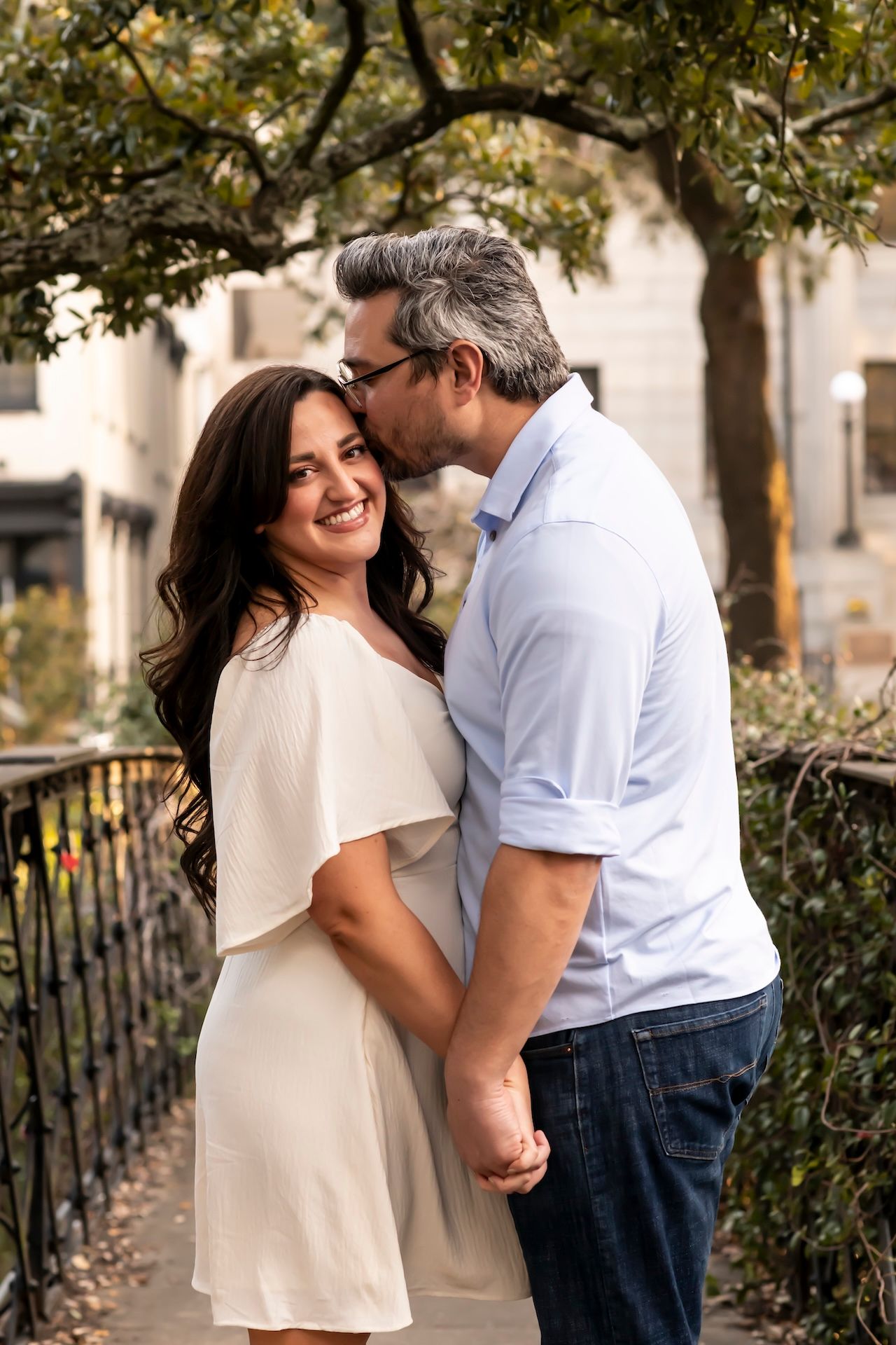 A couple shares tender moments together during a romantic outdoor photo session along a tree-lined path.