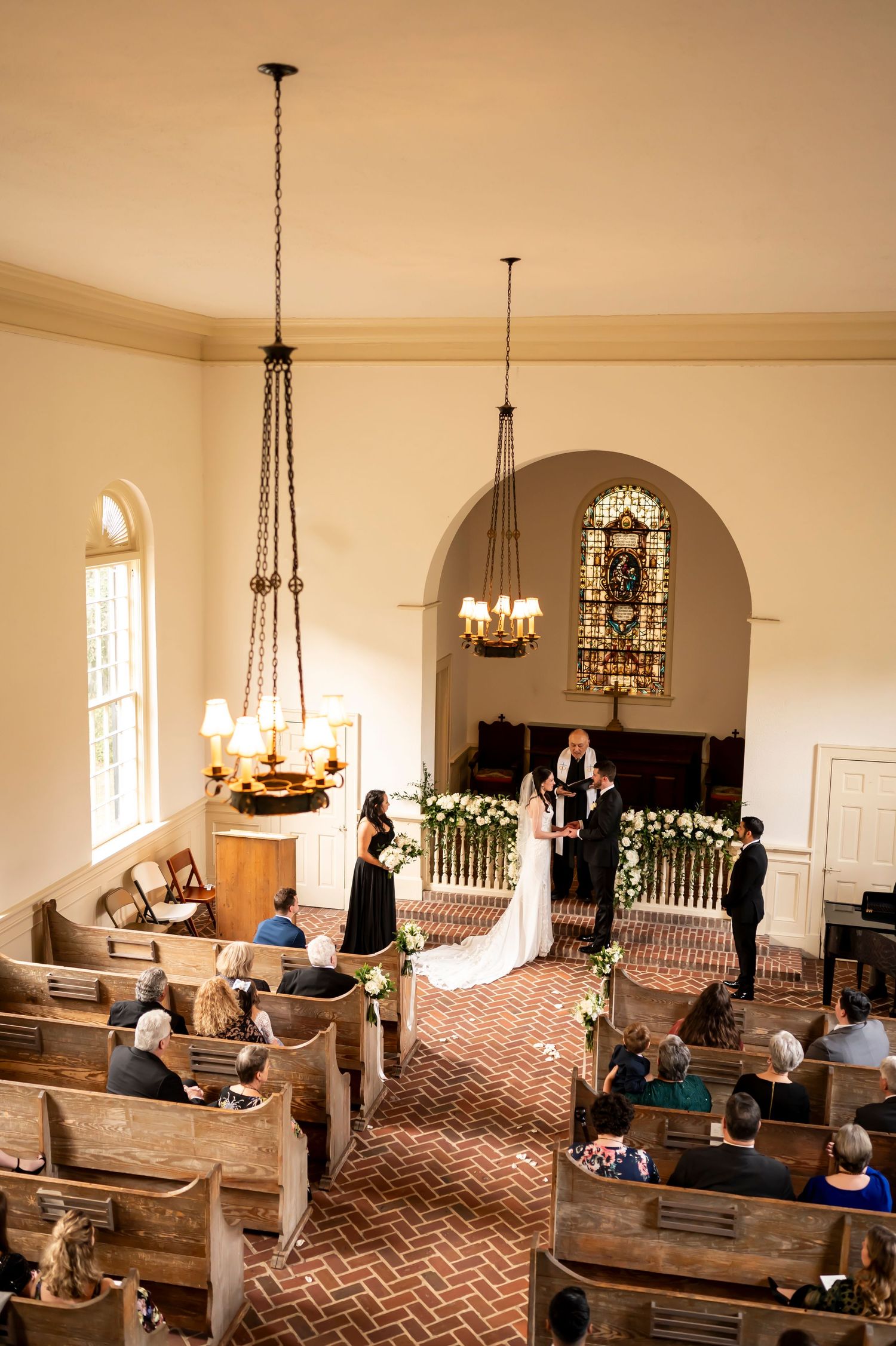 Interior view of a traditional church wedding ceremony with wooden pews and stained glass windows in warm lighting.