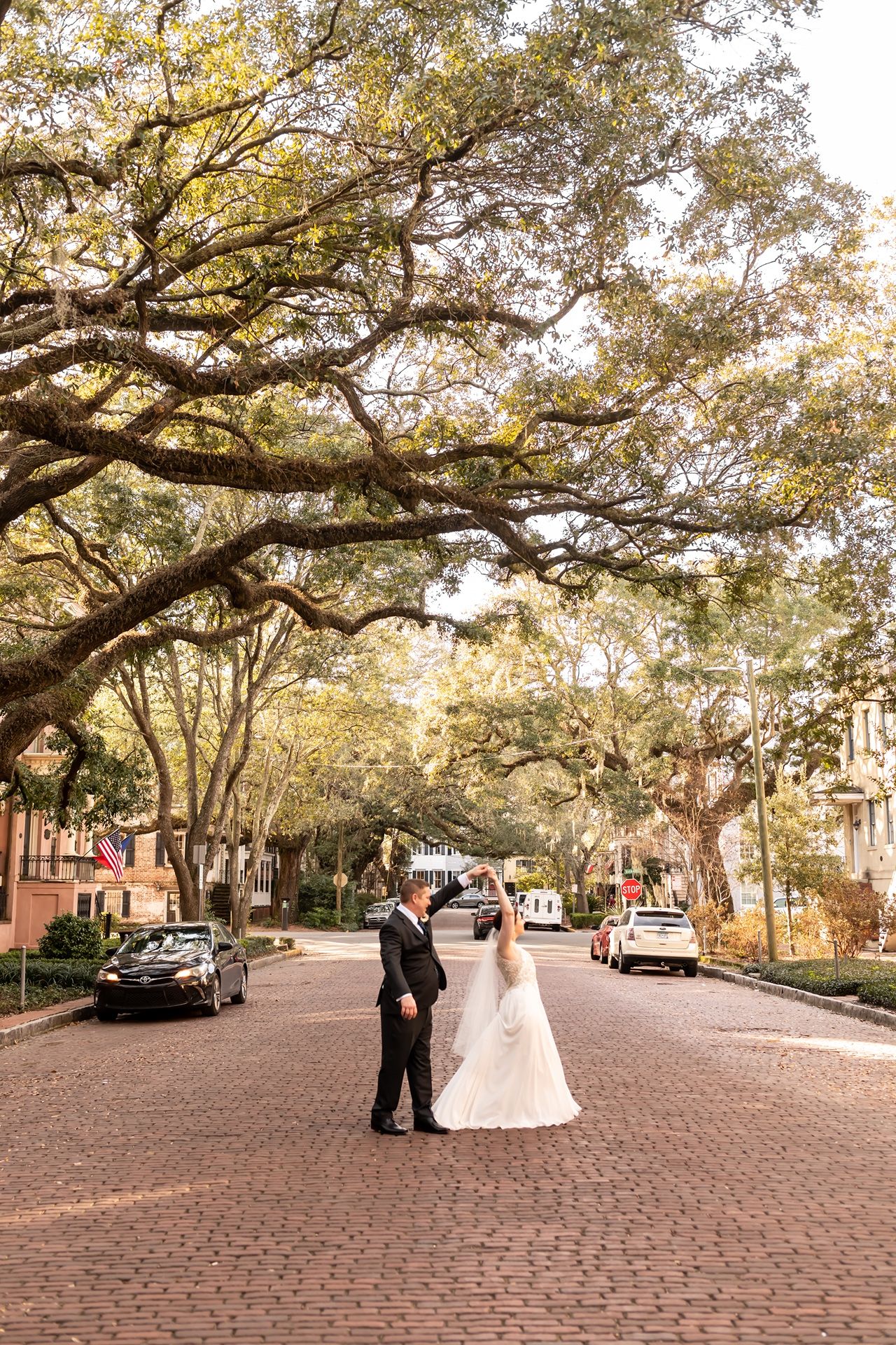 A romantic wedding photo sequence on a tree-lined cobblestone street in a historic downtown setting during autumn.