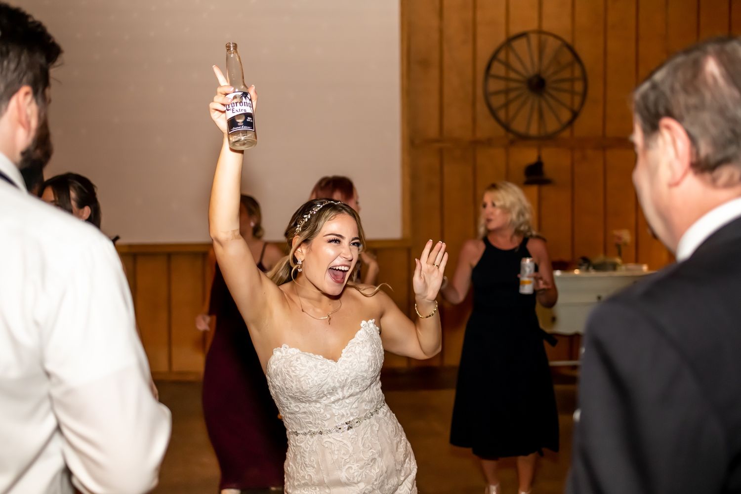 A couple dances together during a wedding reception at an indoor venue with wood paneled walls.