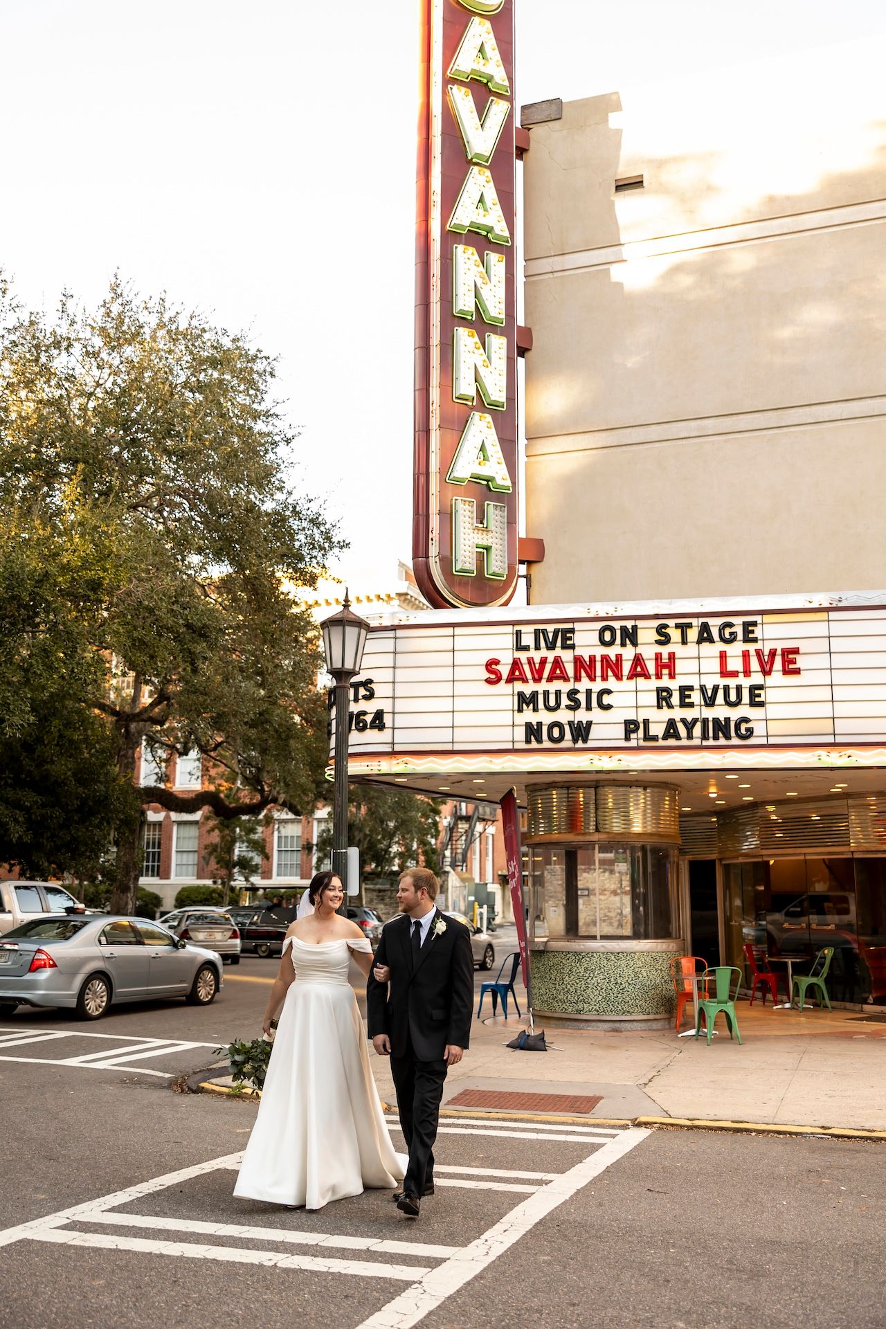 Historic Savannah Theatre with its classic vertical sign displays 'Live on Stage' marquee on a tree-lined street.