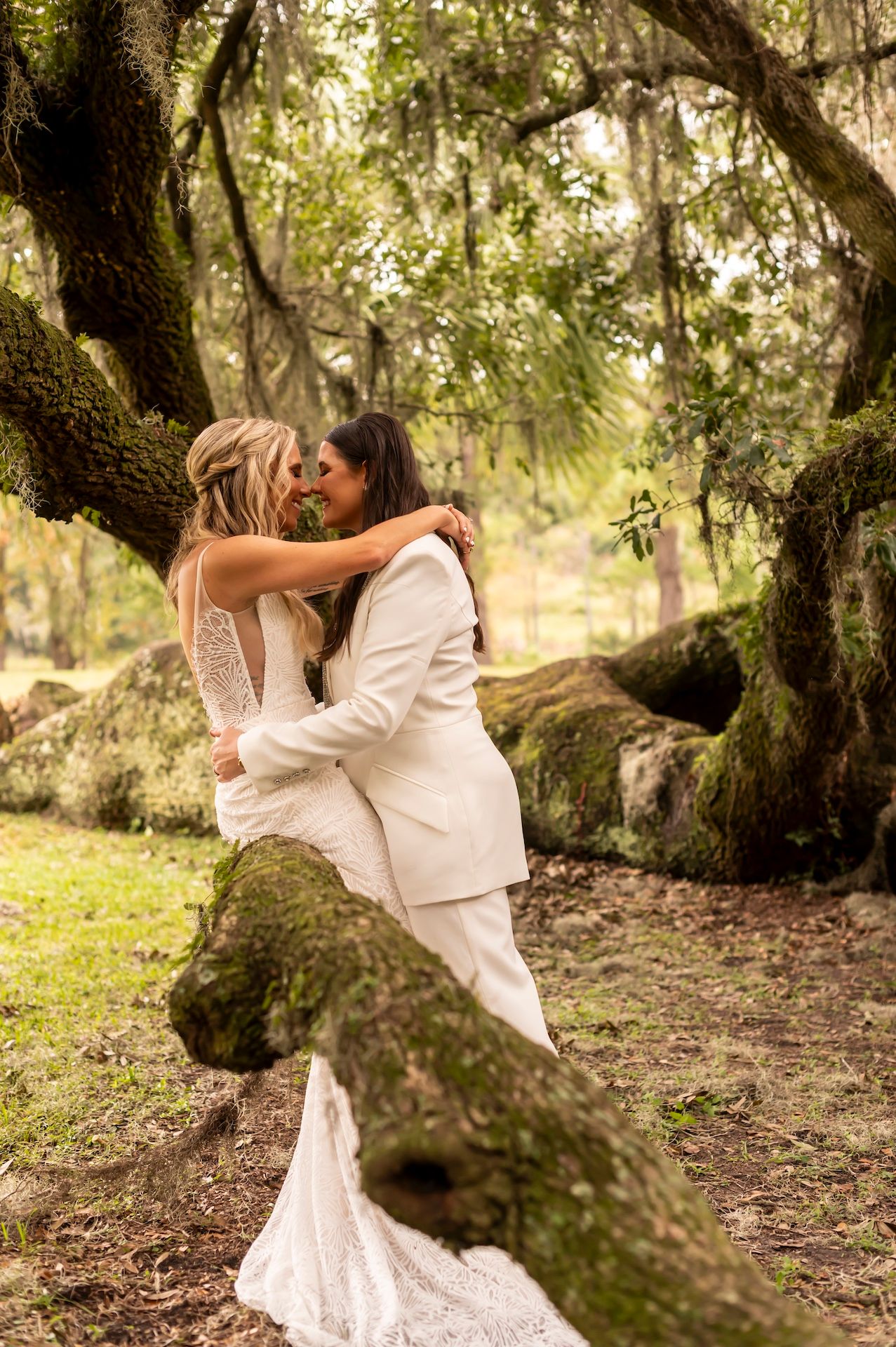 A romantic moment captured beneath a moss-draped oak tree with Spanish moss hanging overhead in a natural garden setting.