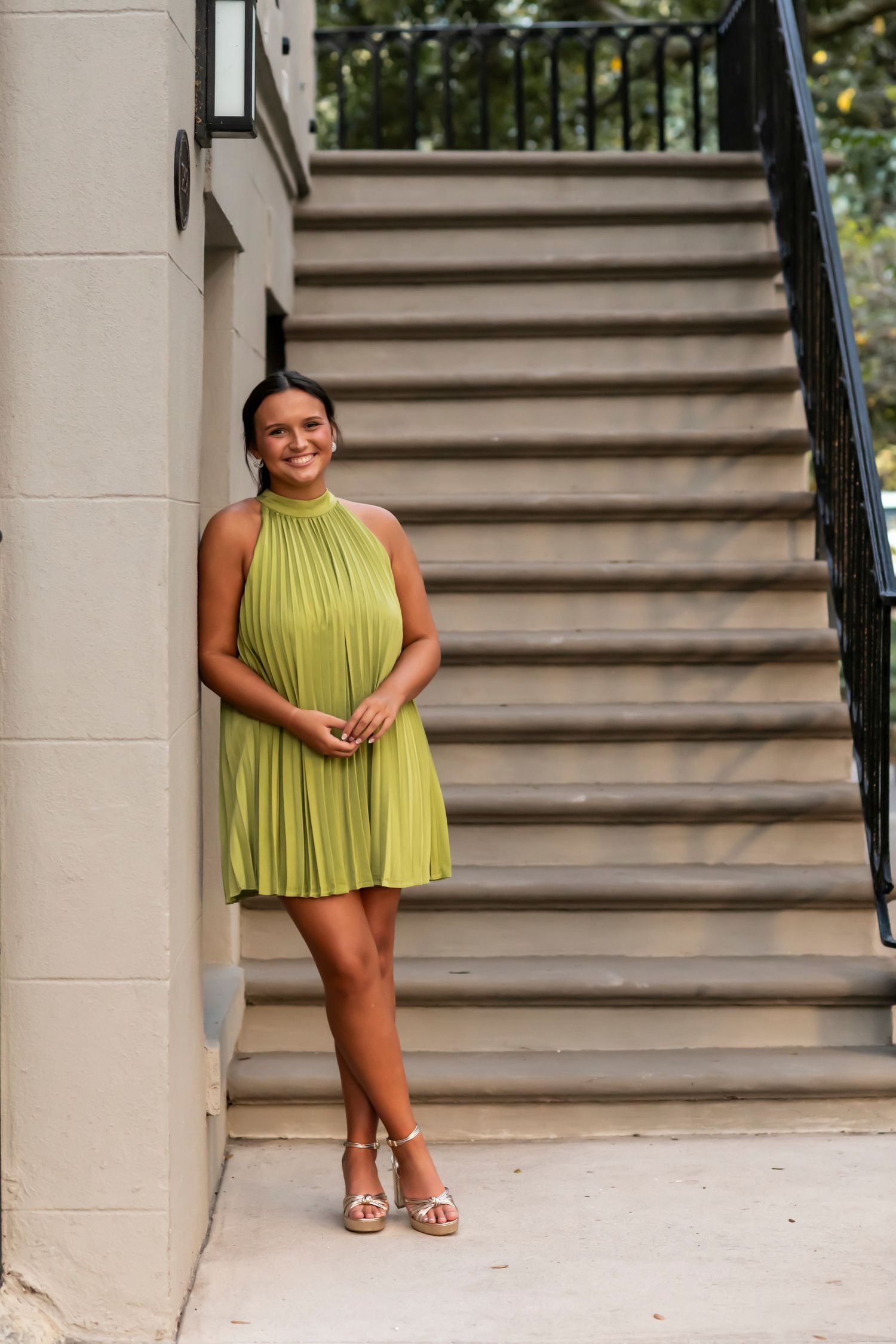 A fashion portrait featuring a lime green pleated dress on classic stone steps.