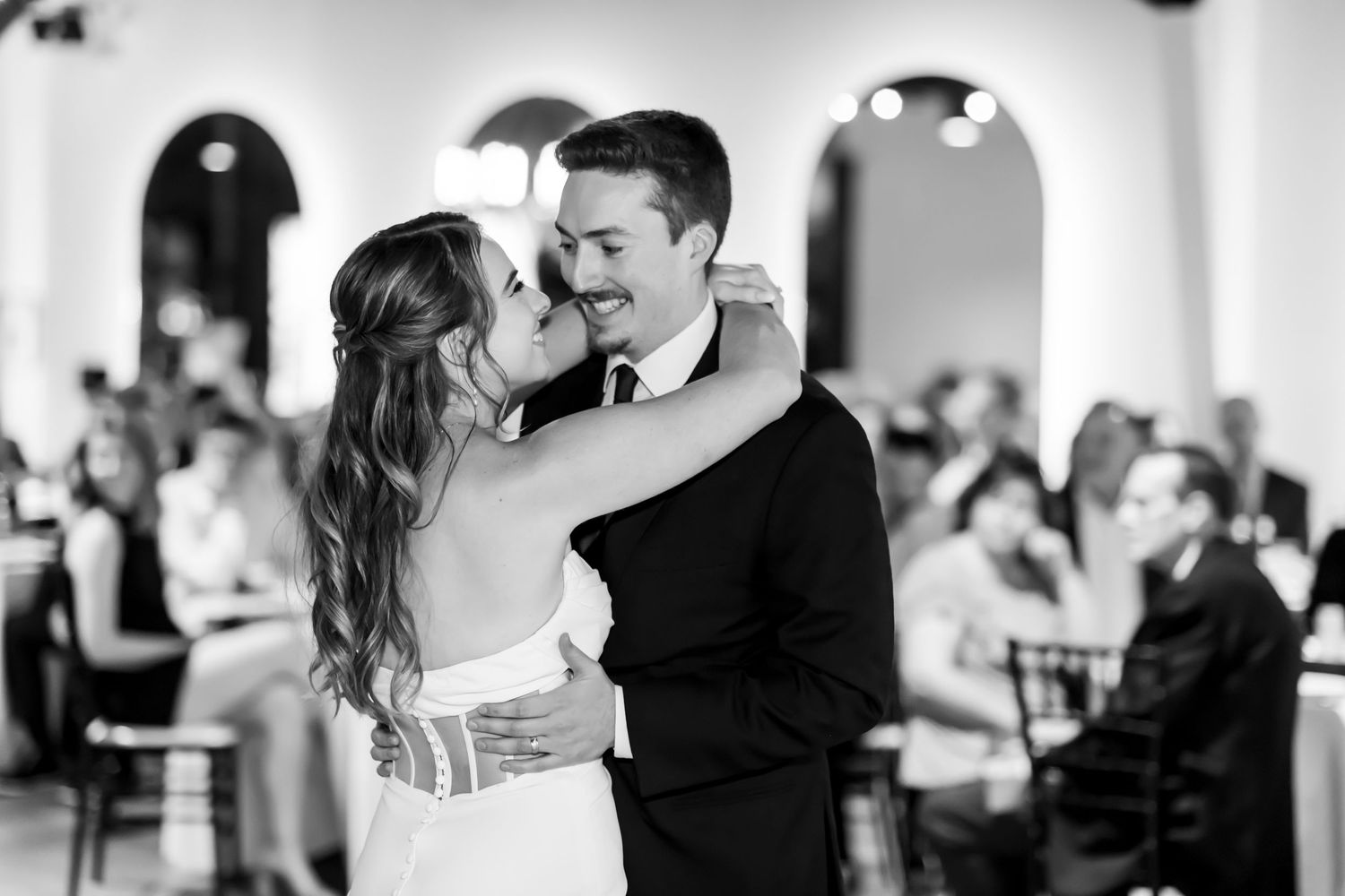 Black and white photo of a couple sharing their first dance at a wedding reception.