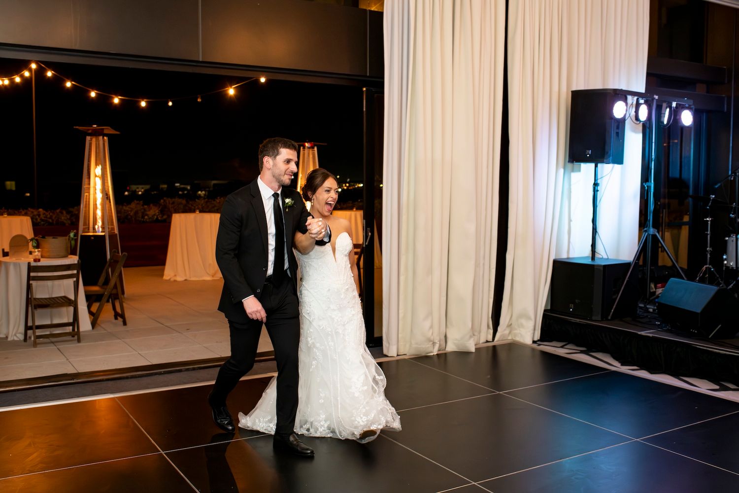 Wedding reception dance floor with guests dancing under ambient lighting and string lights.