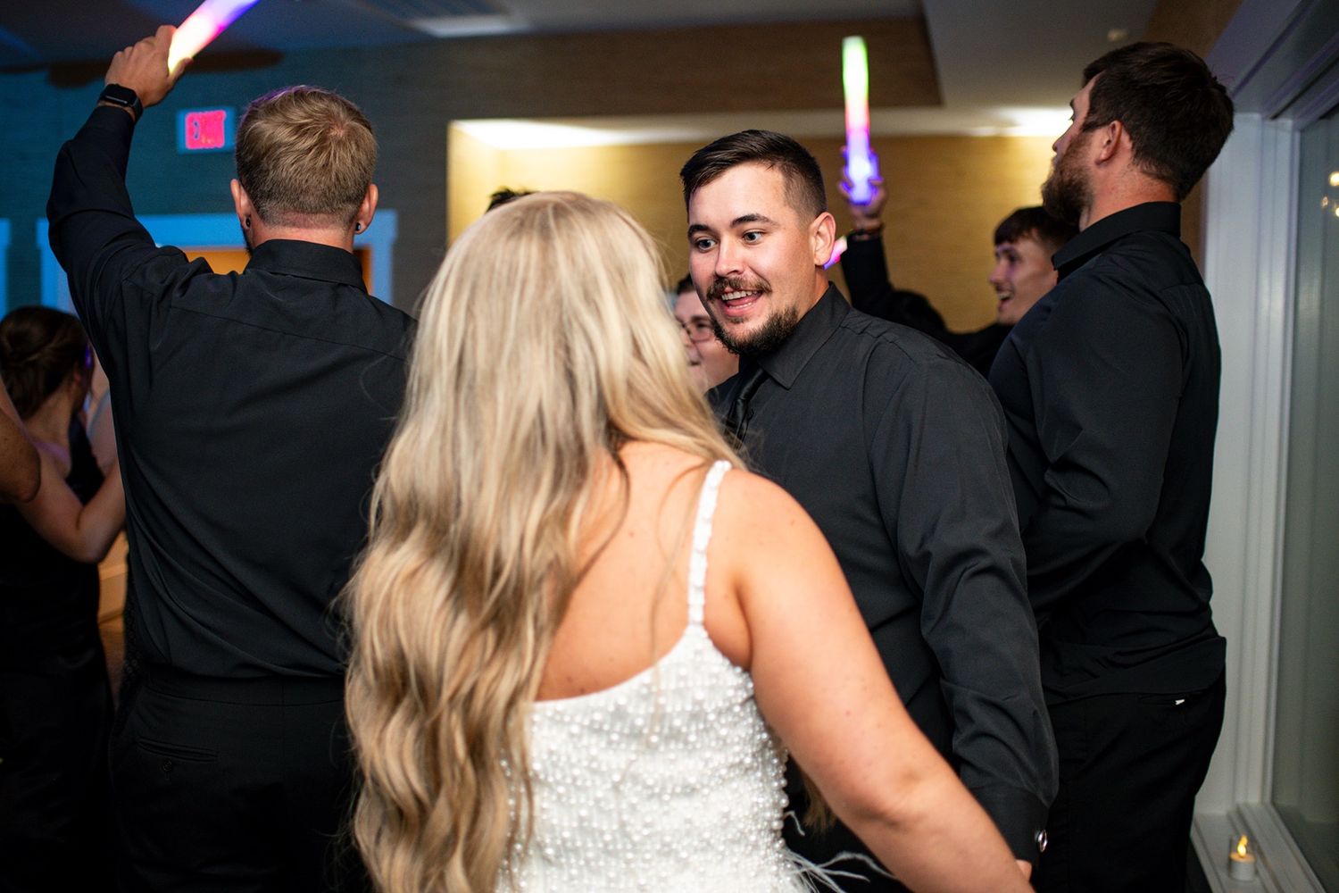 Wedding celebration in a reception hall with guests dancing under ambient lighting.
