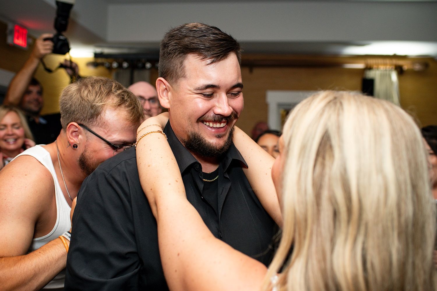 A group of people sharing warm embraces and hugs at what appears to be a social gathering or celebration.
