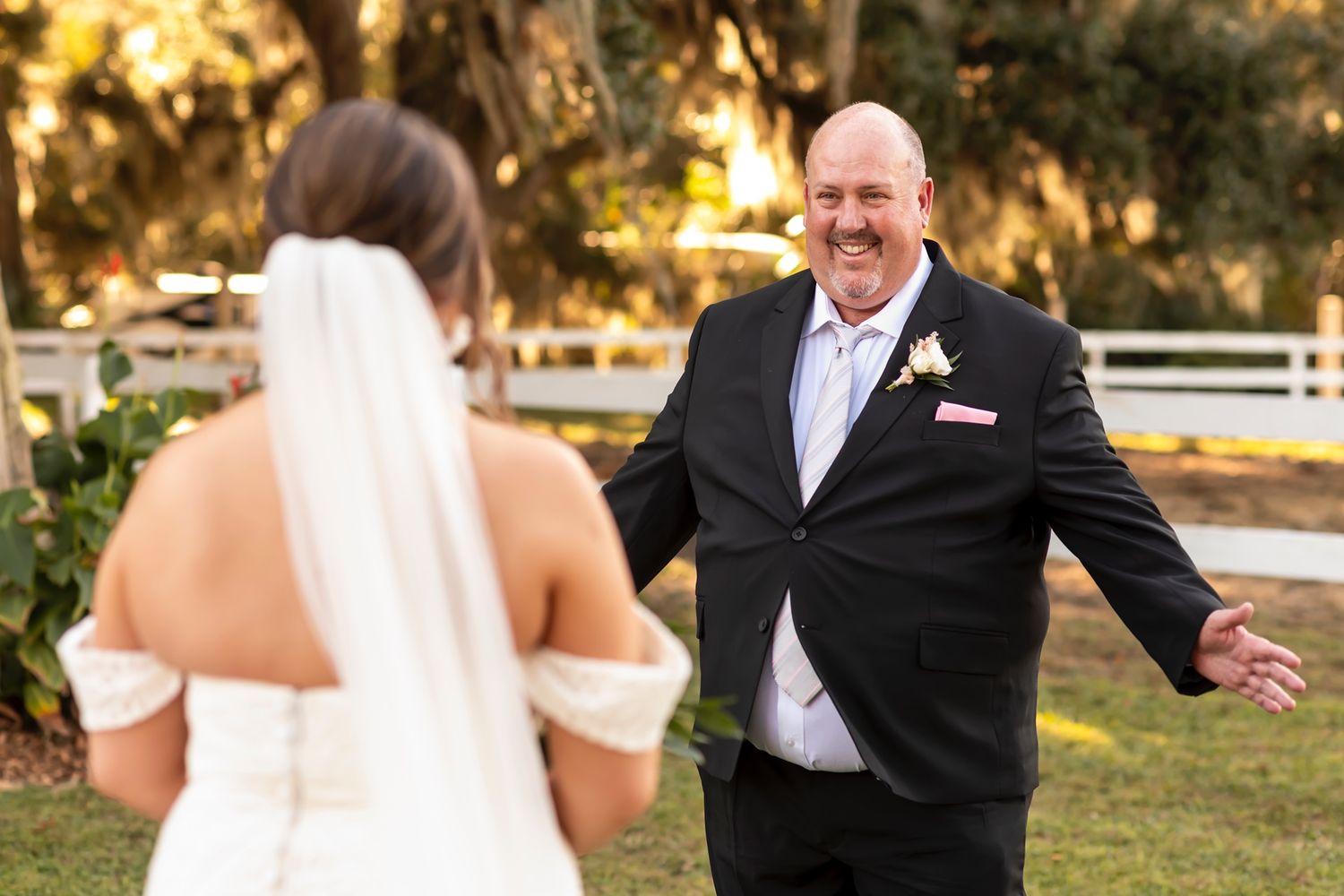 A joyful groom reacts with excitement during a first look wedding moment outdoors at sunset.