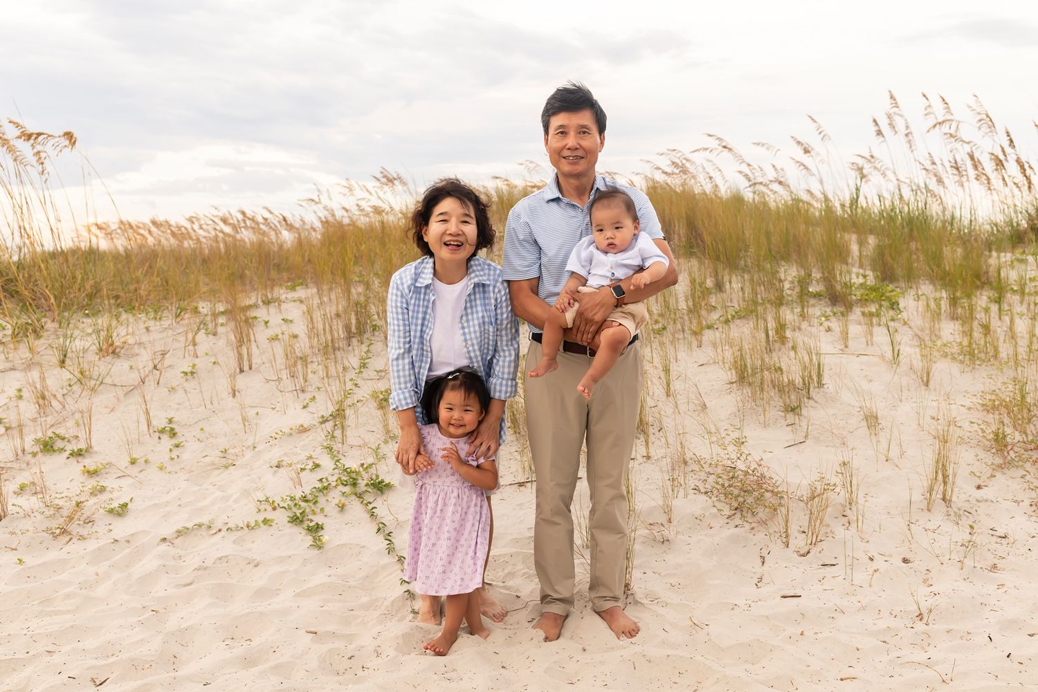 A group poses together on coastal sand dunes with sea oats swaying in the background.
