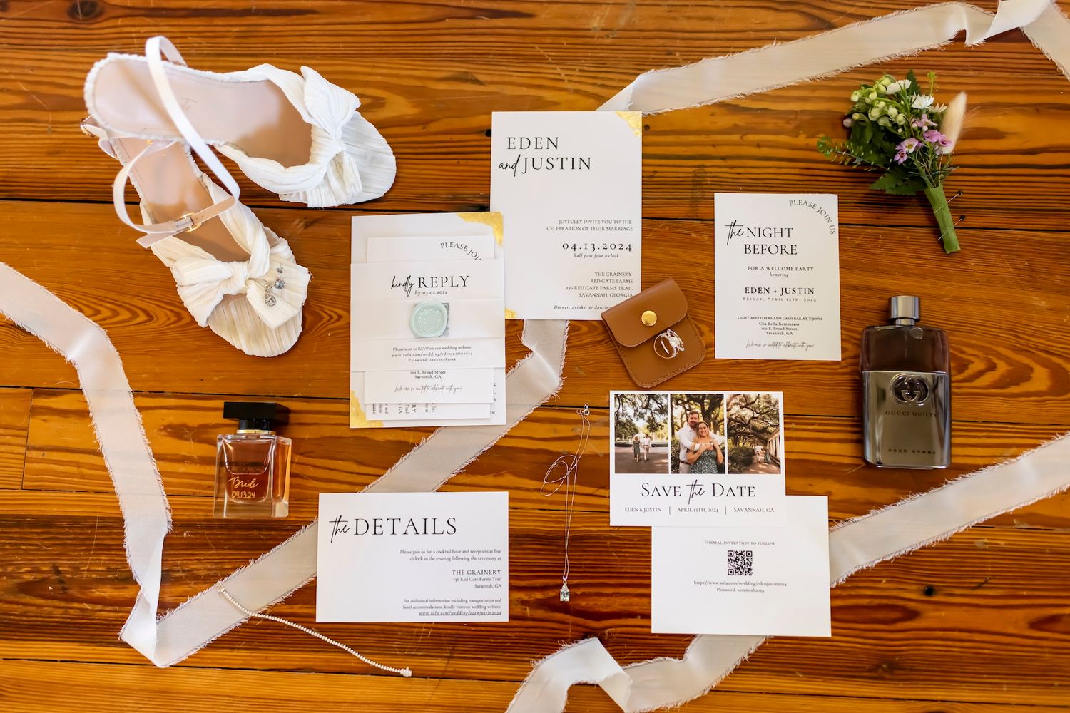 Wedding details flatlay with invitations, ballet shoes, perfume bottle and small floral bouquet on wooden surface.