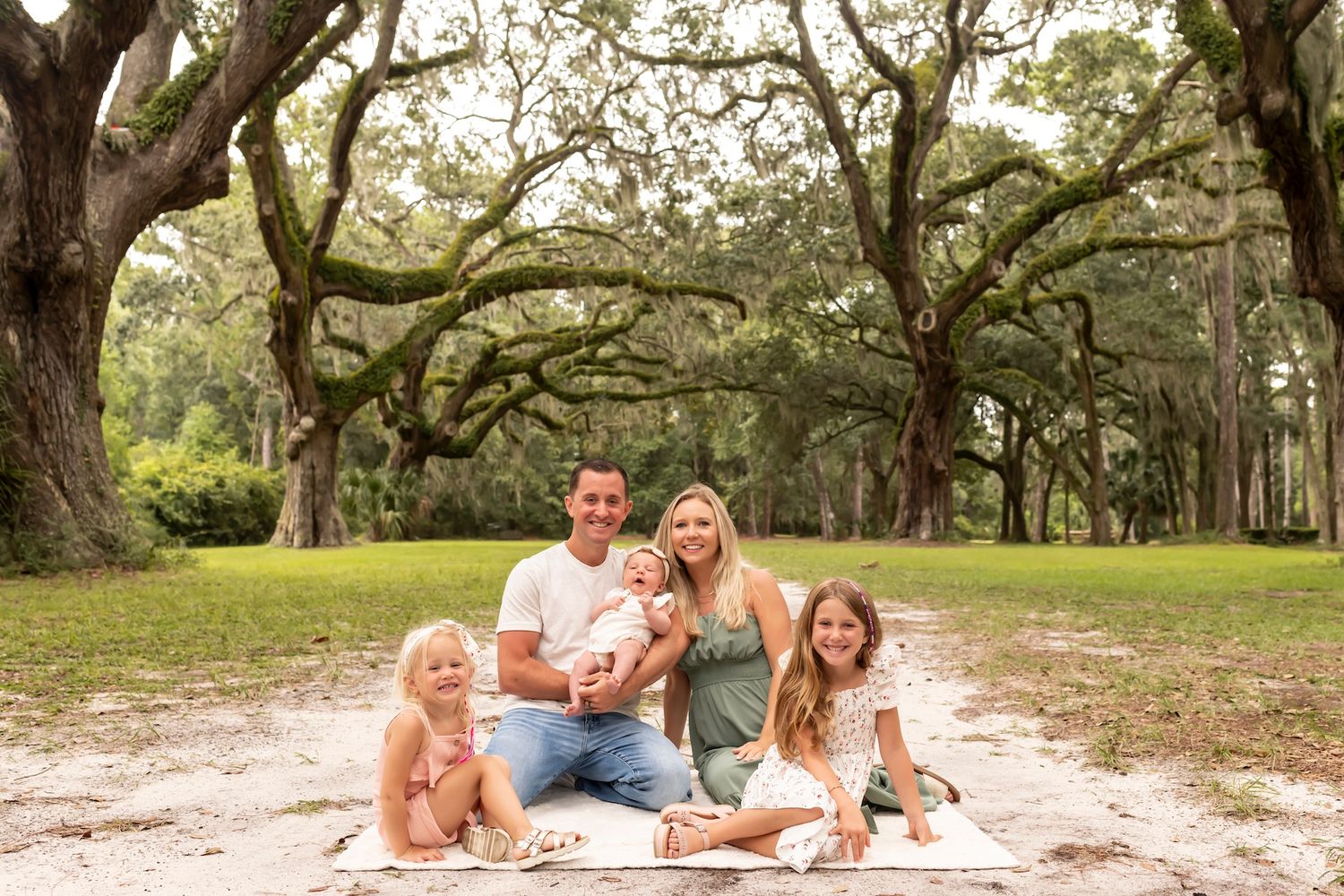 A tender family photoshoot in a park with Spanish moss covered trees in the background.