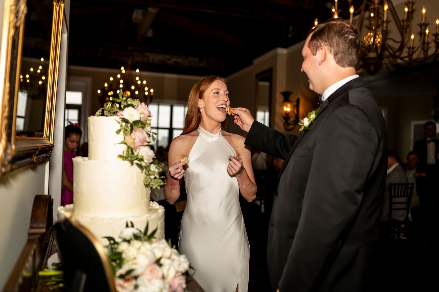 Happy couple sharing a joyful moment while celebrating near their wedding cake in an elegant venue.