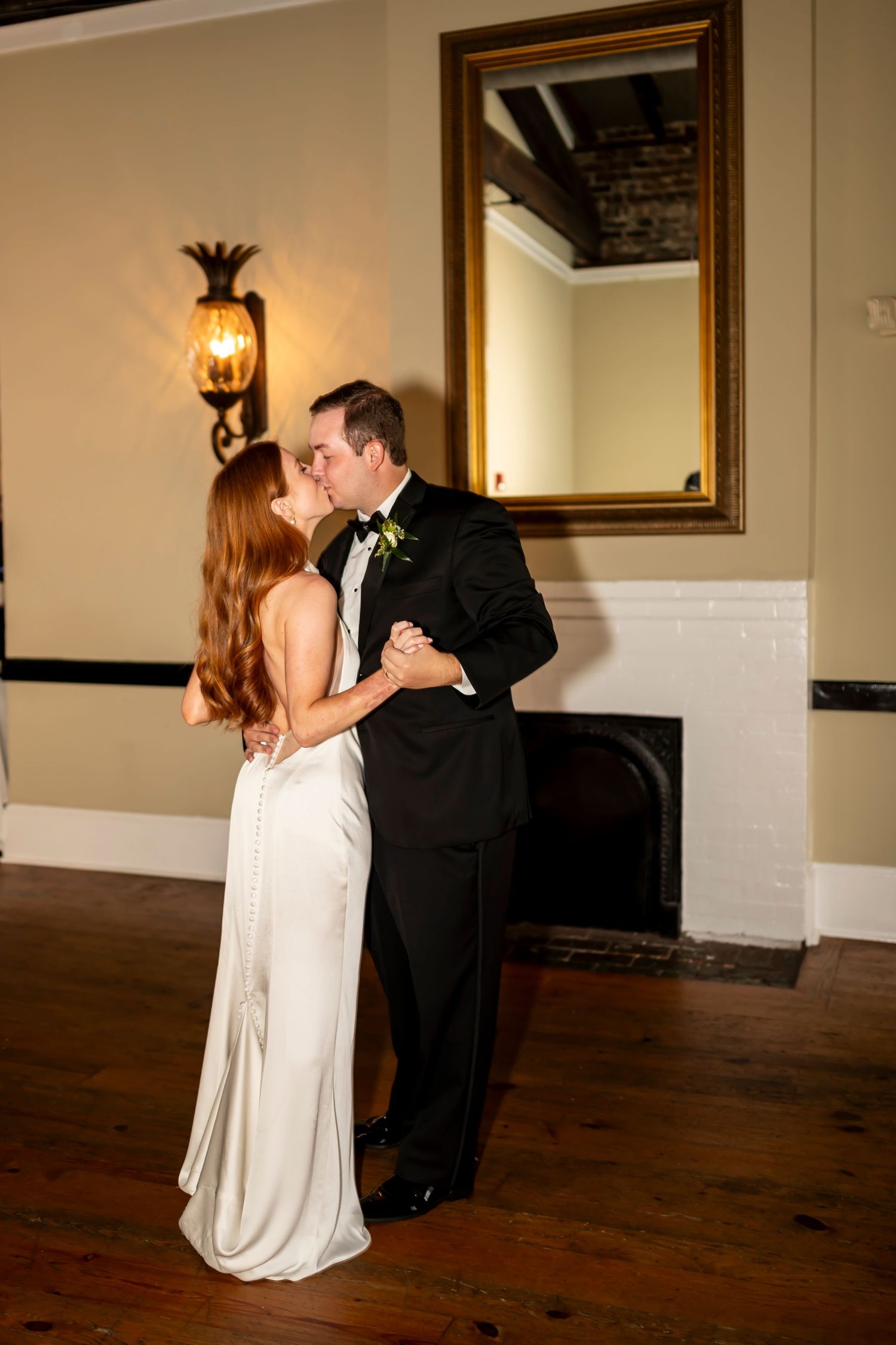 Wedding couple shares romantic kisses in sequence of five frames inside elegant venue with wood floors and warm lighting.