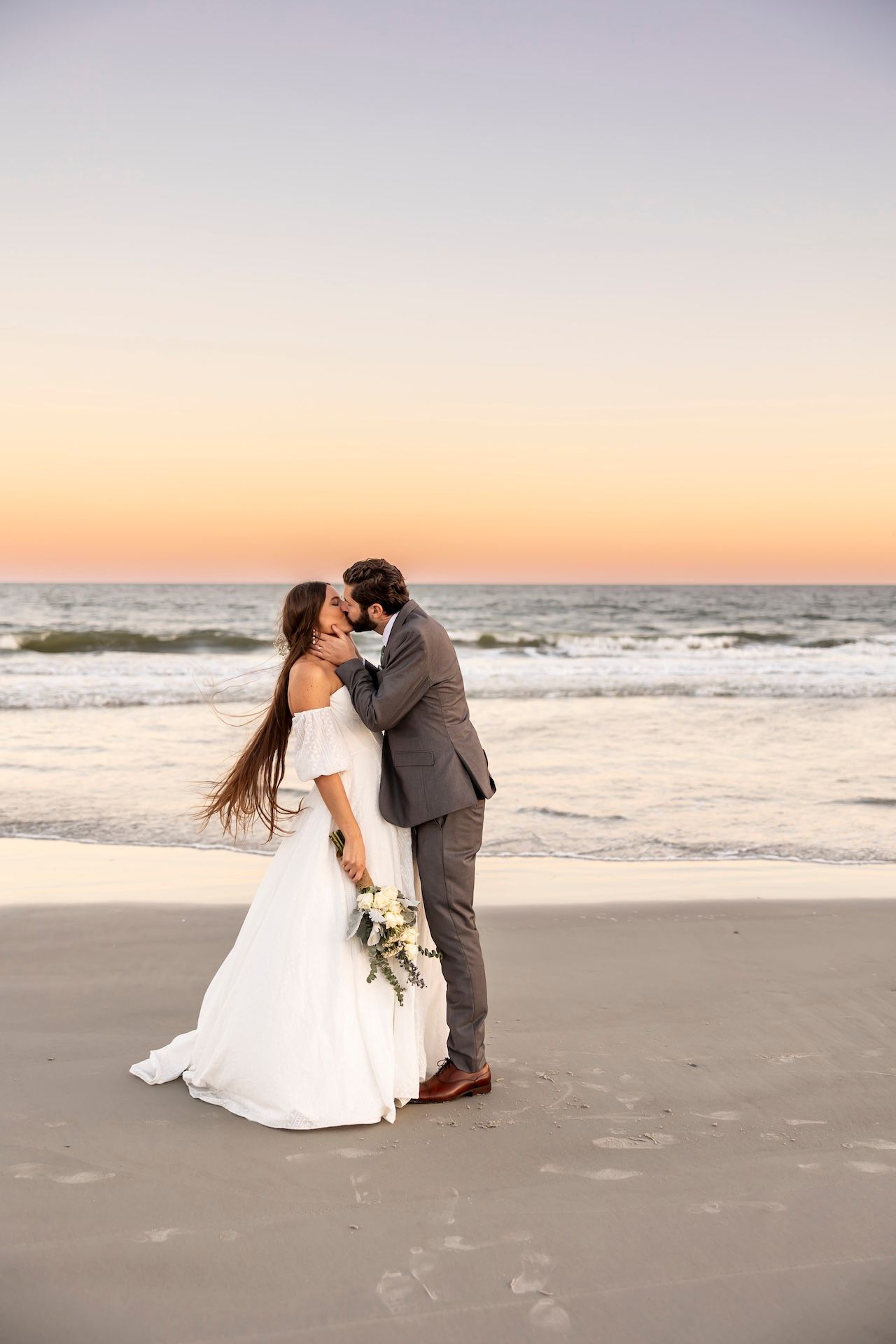 Newlyweds share romantic moments on a sunset beach with crashing waves and soft sand.