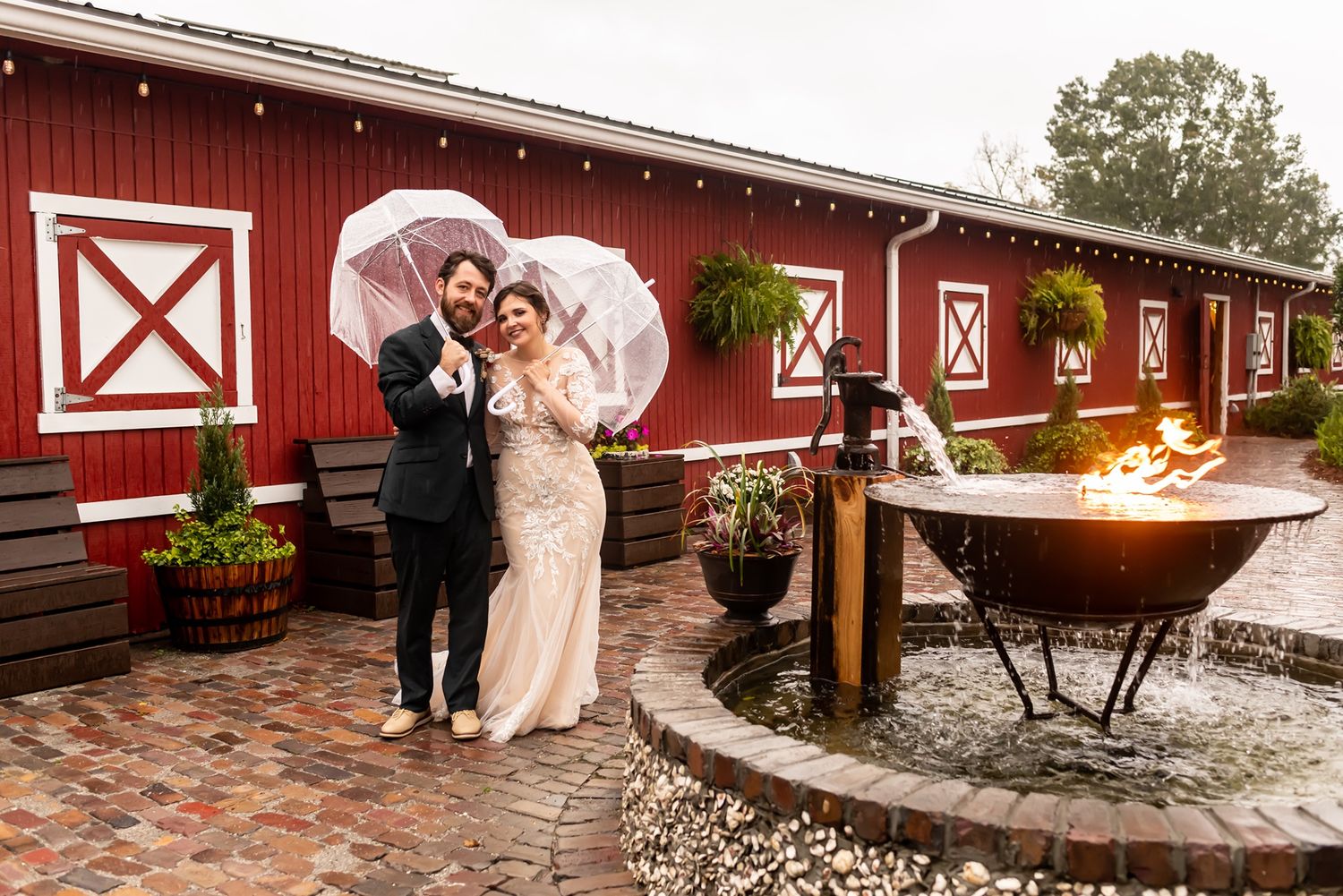 Red barn wedding venue exterior with decorative outdoor lighting and stone patio area.