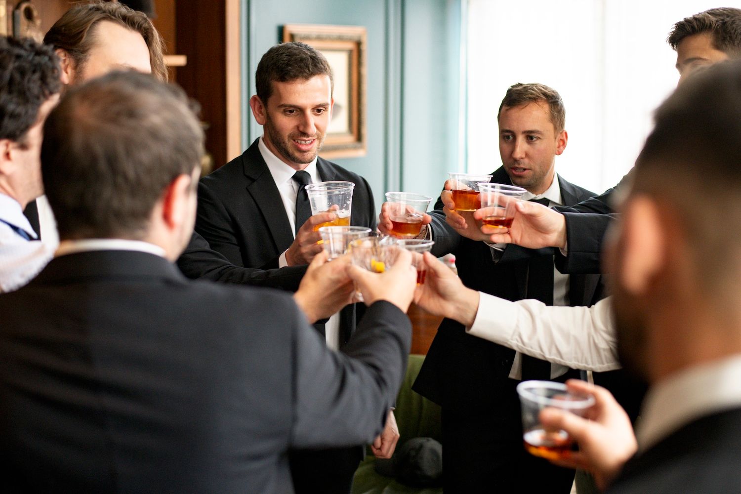 Groomsmen raise glasses in a celebratory toast during a wedding reception.