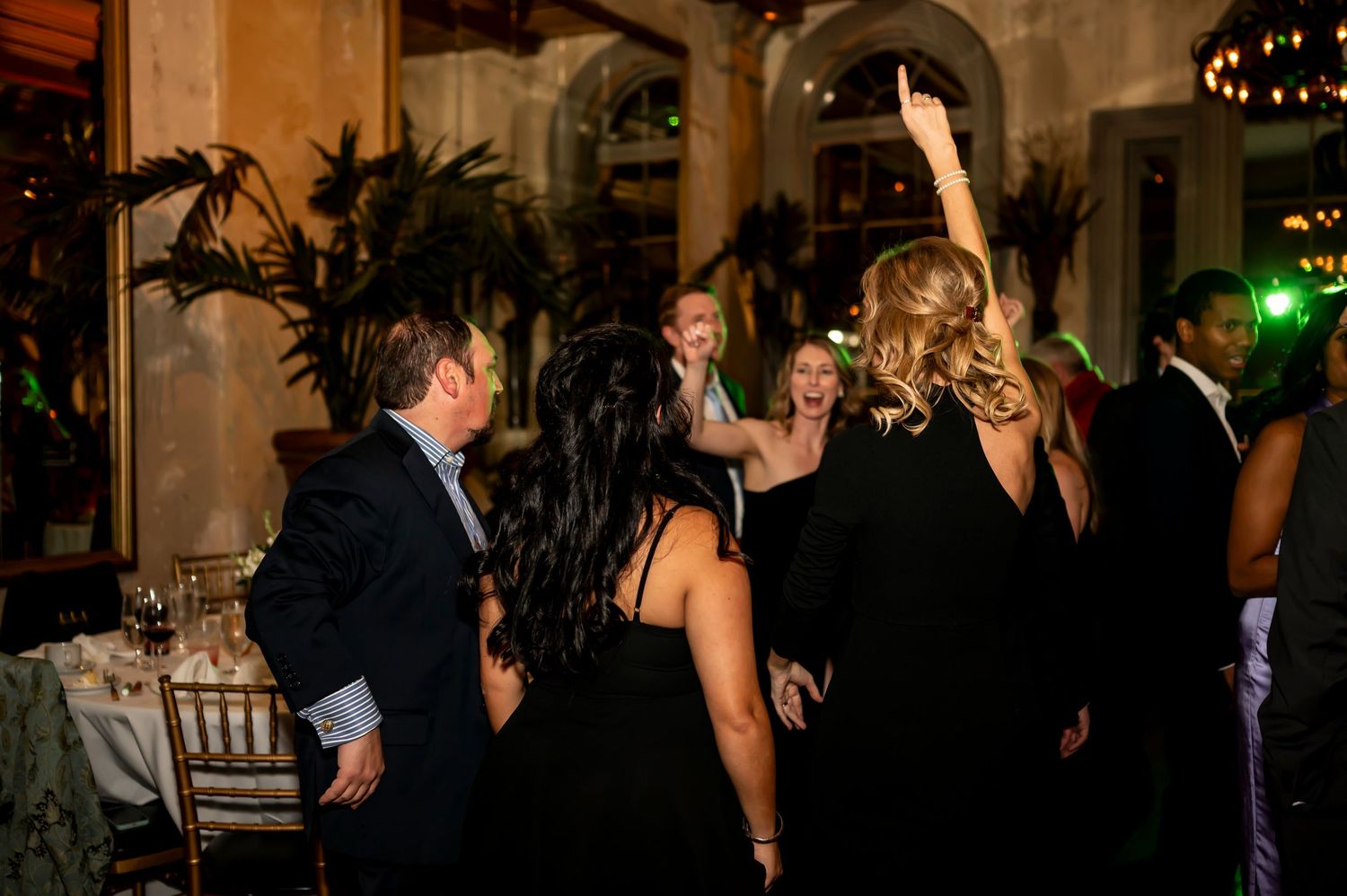 People dancing and celebrating at an elegant evening party in a dimly lit venue with decorative lighting.