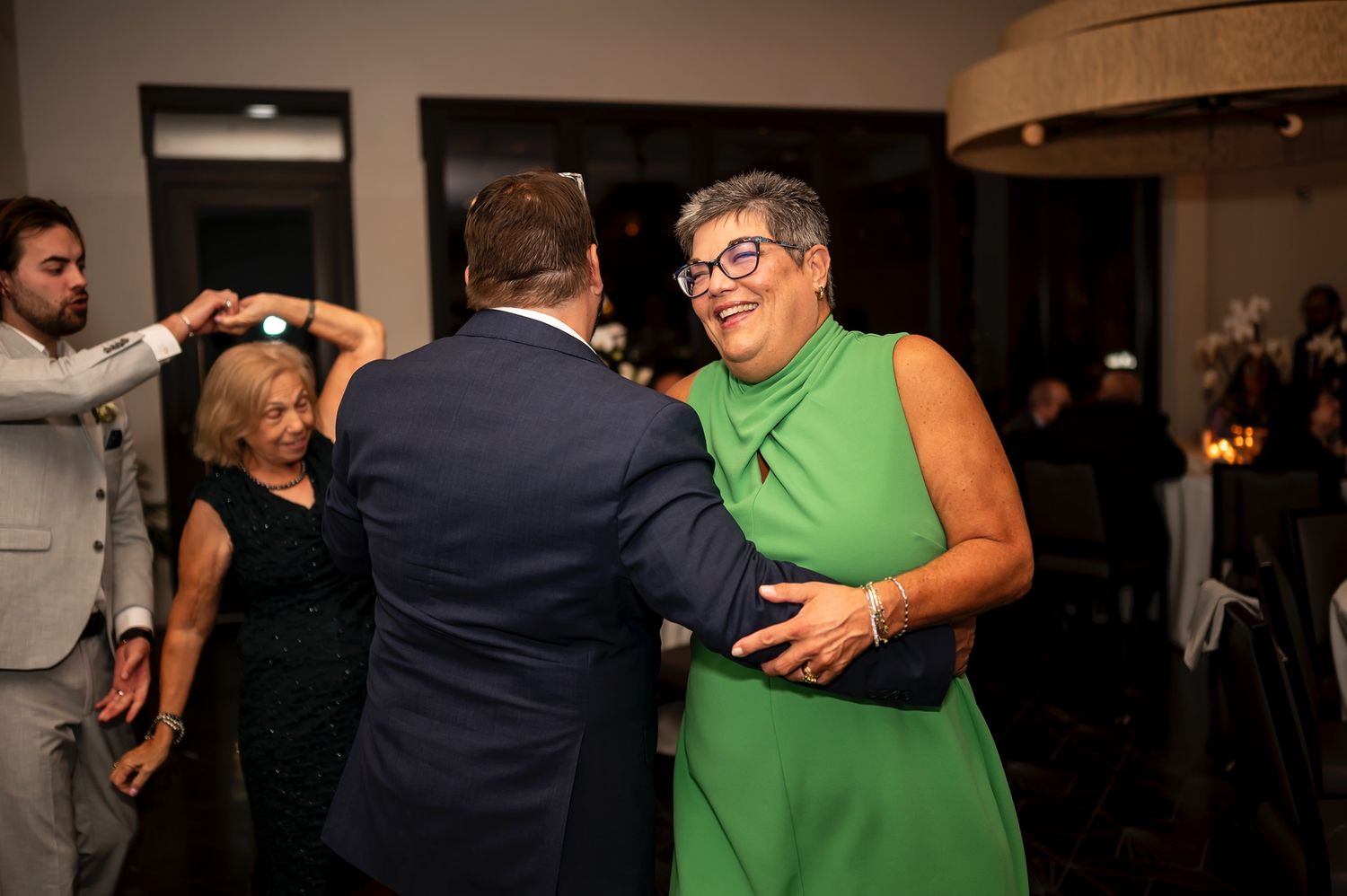 People dancing together in what appears to be a dance class or social event in a dimly lit room.