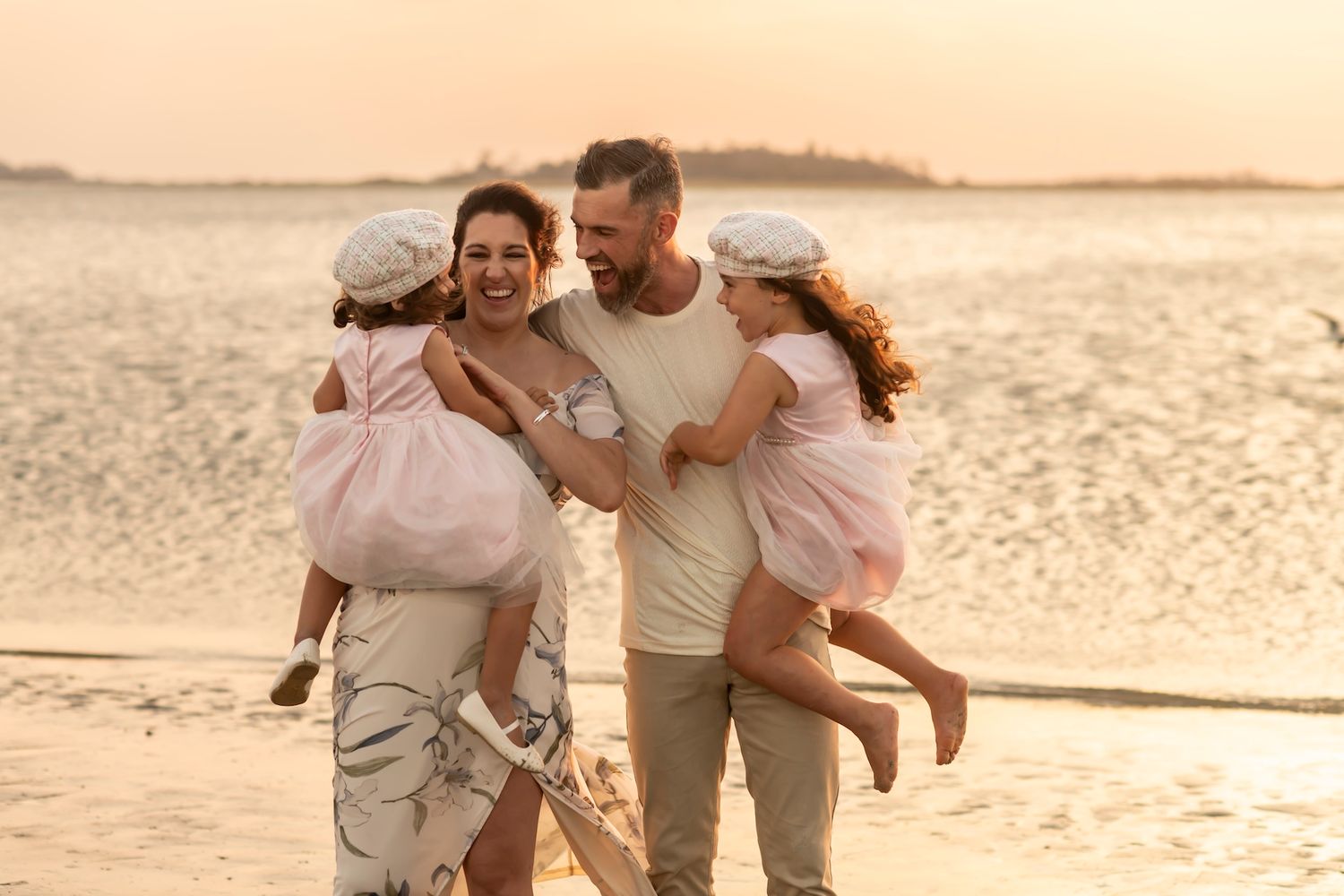 Couple running and playing together on a sandy beach during golden sunset hour.