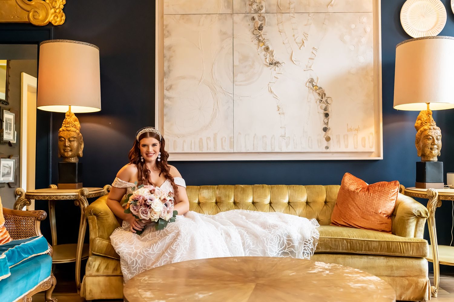 Modern lounge area with white marble wall, tufted sofa, table lamps and decorative artwork.