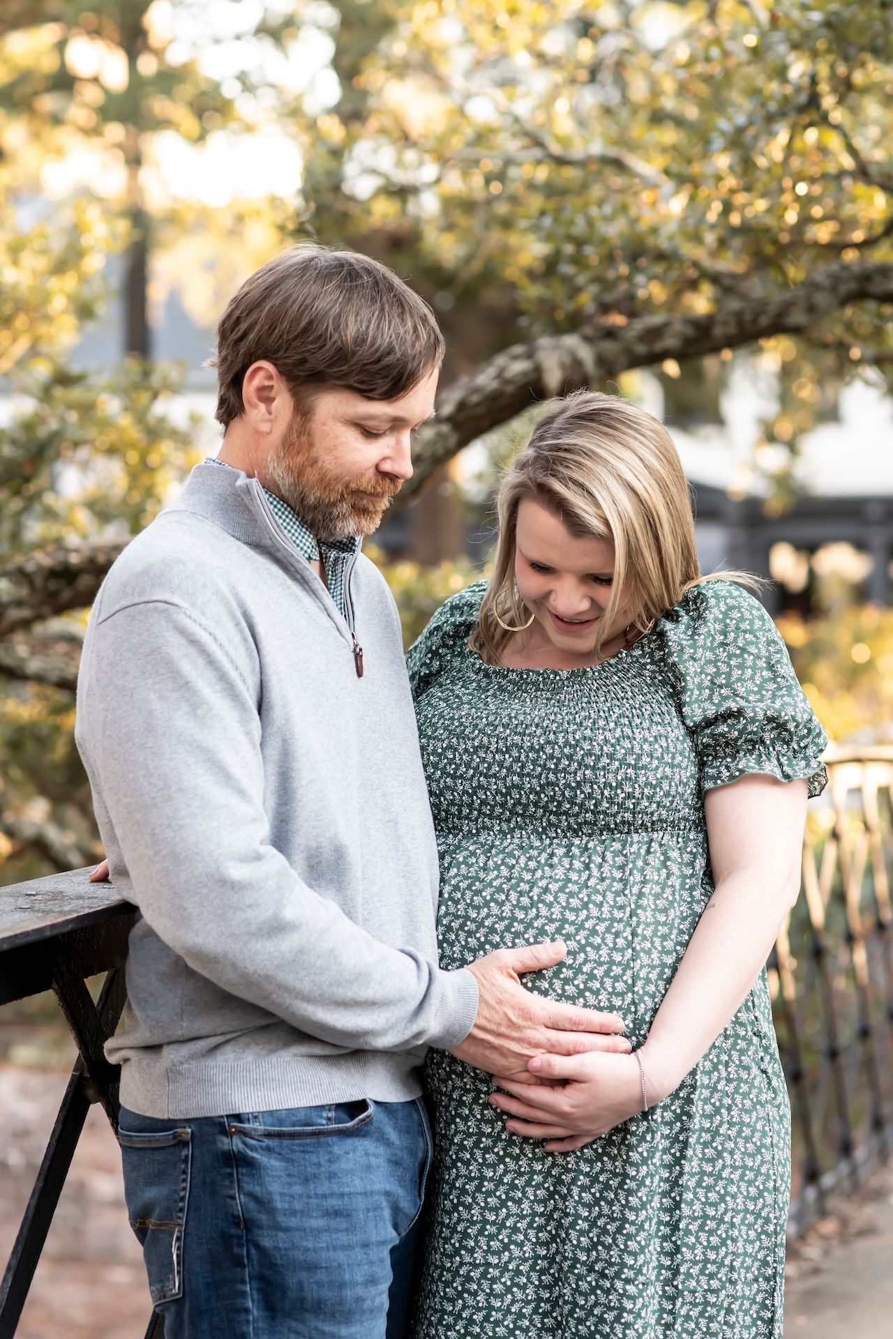 Expectant couple sharing tender moment while touching baby bump in autumn setting.