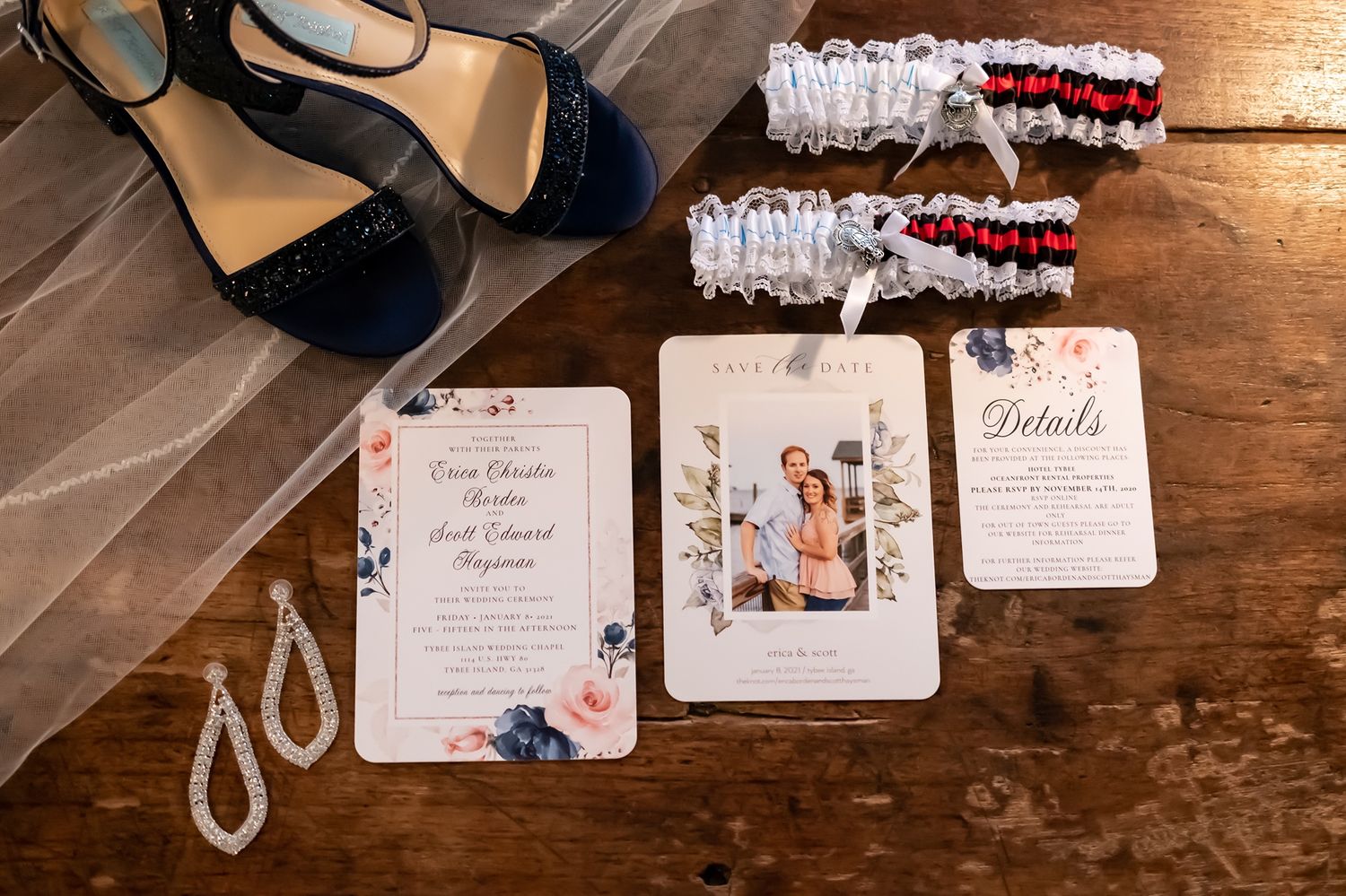 Wedding stationery and garters arranged on rustic wooden surface with delicate floral designs and white lace details.