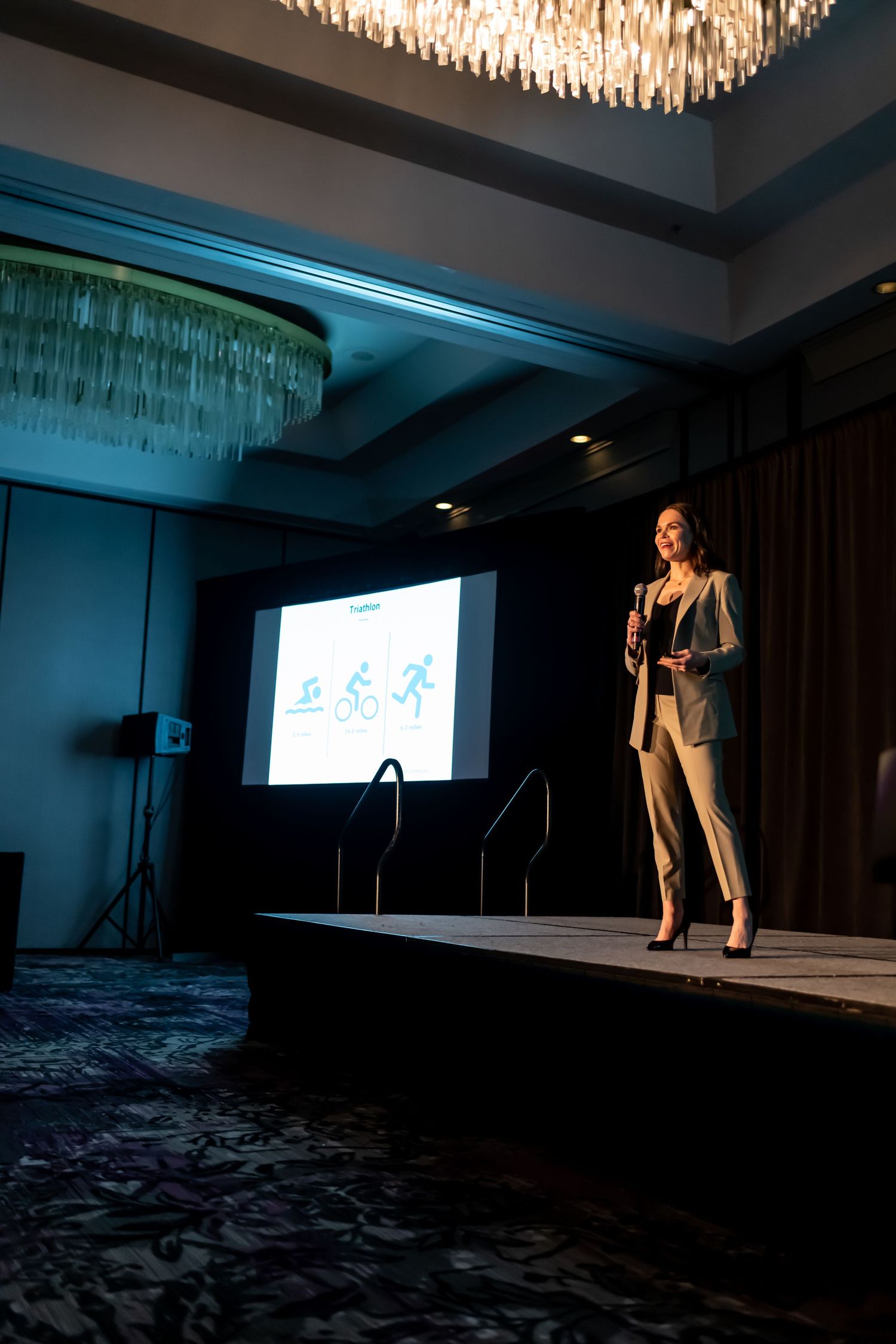 Professional presenter at a corporate event on stage giving presentation in elegant venue with crystal chandeliers in Savannah, Georgia.