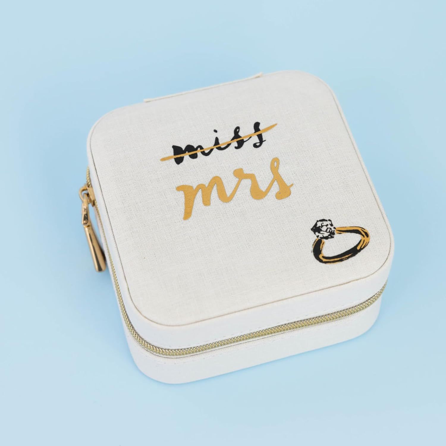 White jewelry travel case with gold 'miss mrs' text and diamond ring illustration on a light blue background.