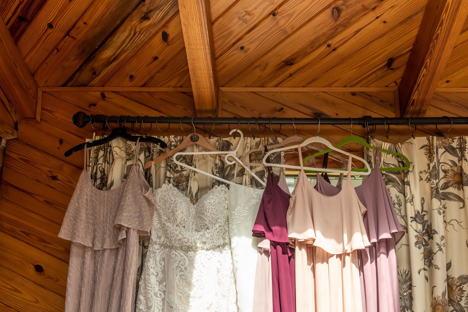 Wooden-beamed room filled with hanging formal dresses and gowns in soft light.