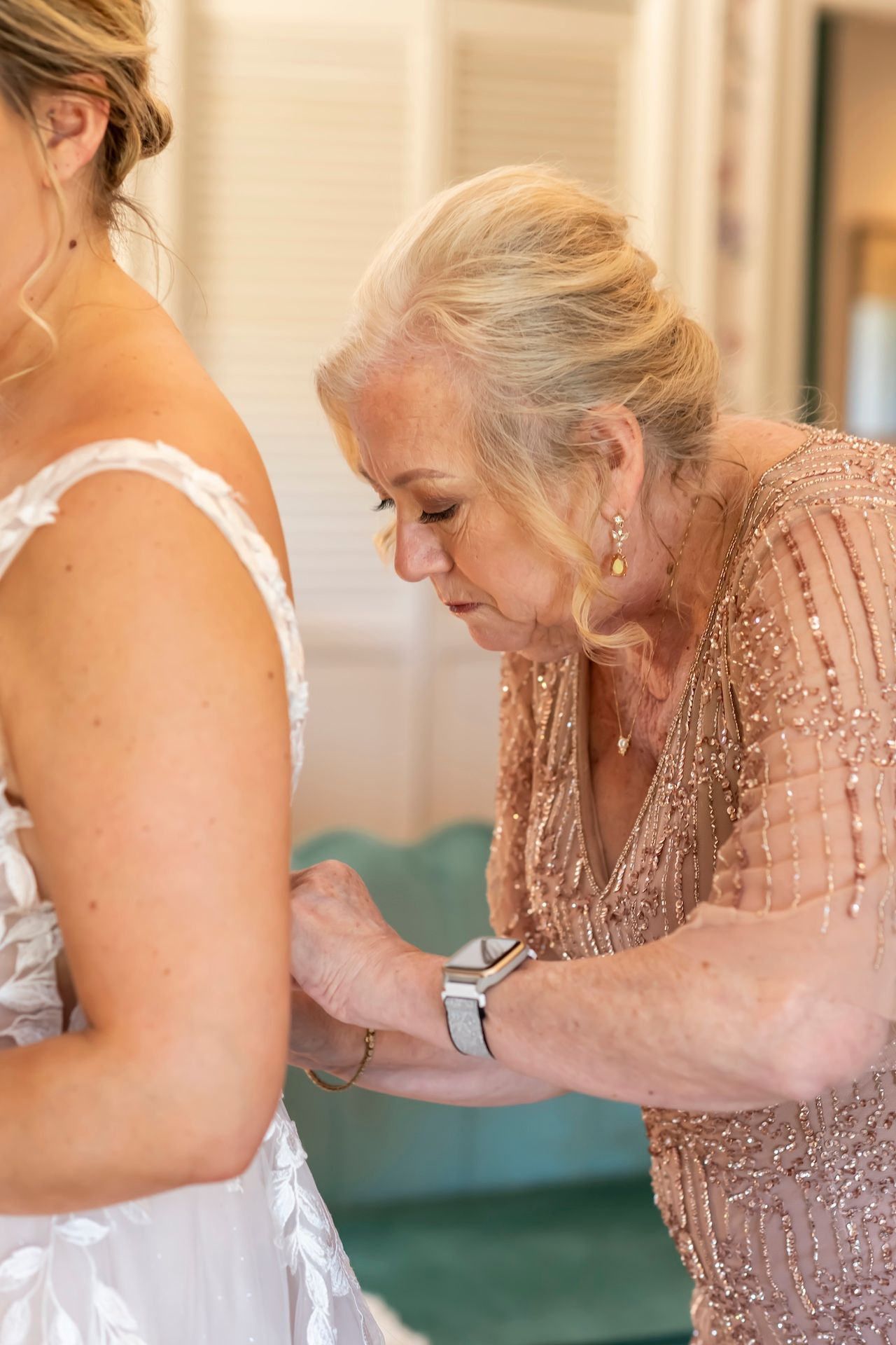 A touching moment of dress preparation shown through delicate final adjustments being made to wedding attire.