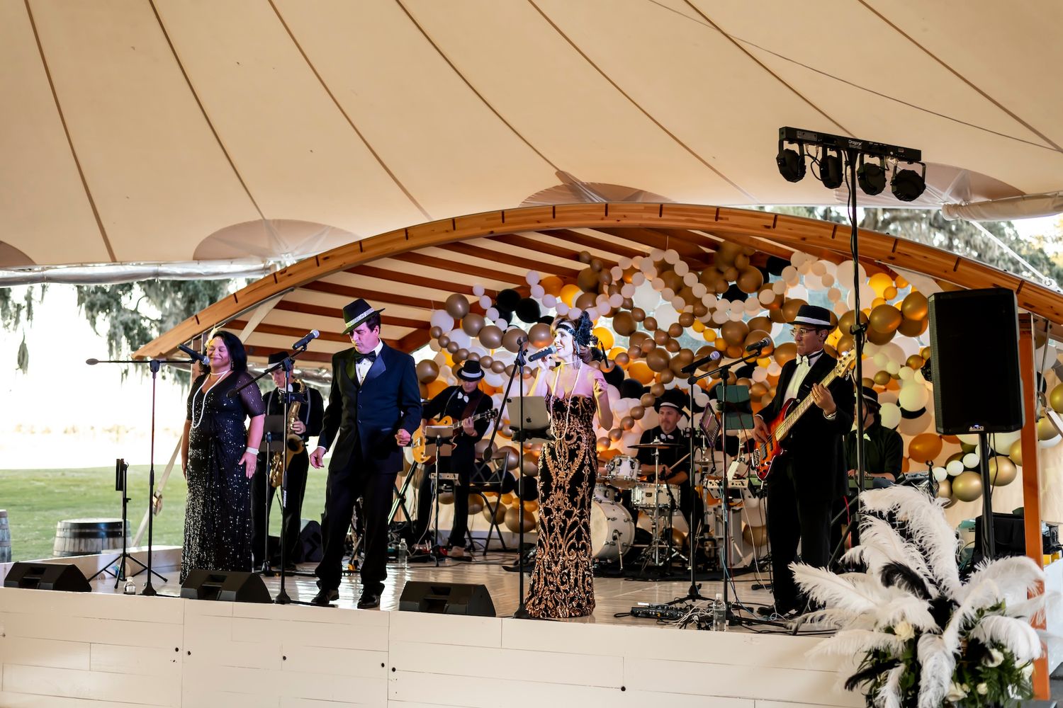 A large panoramic view of an outdoor marketplace with vendors selling clothing and goods under brown canopies.