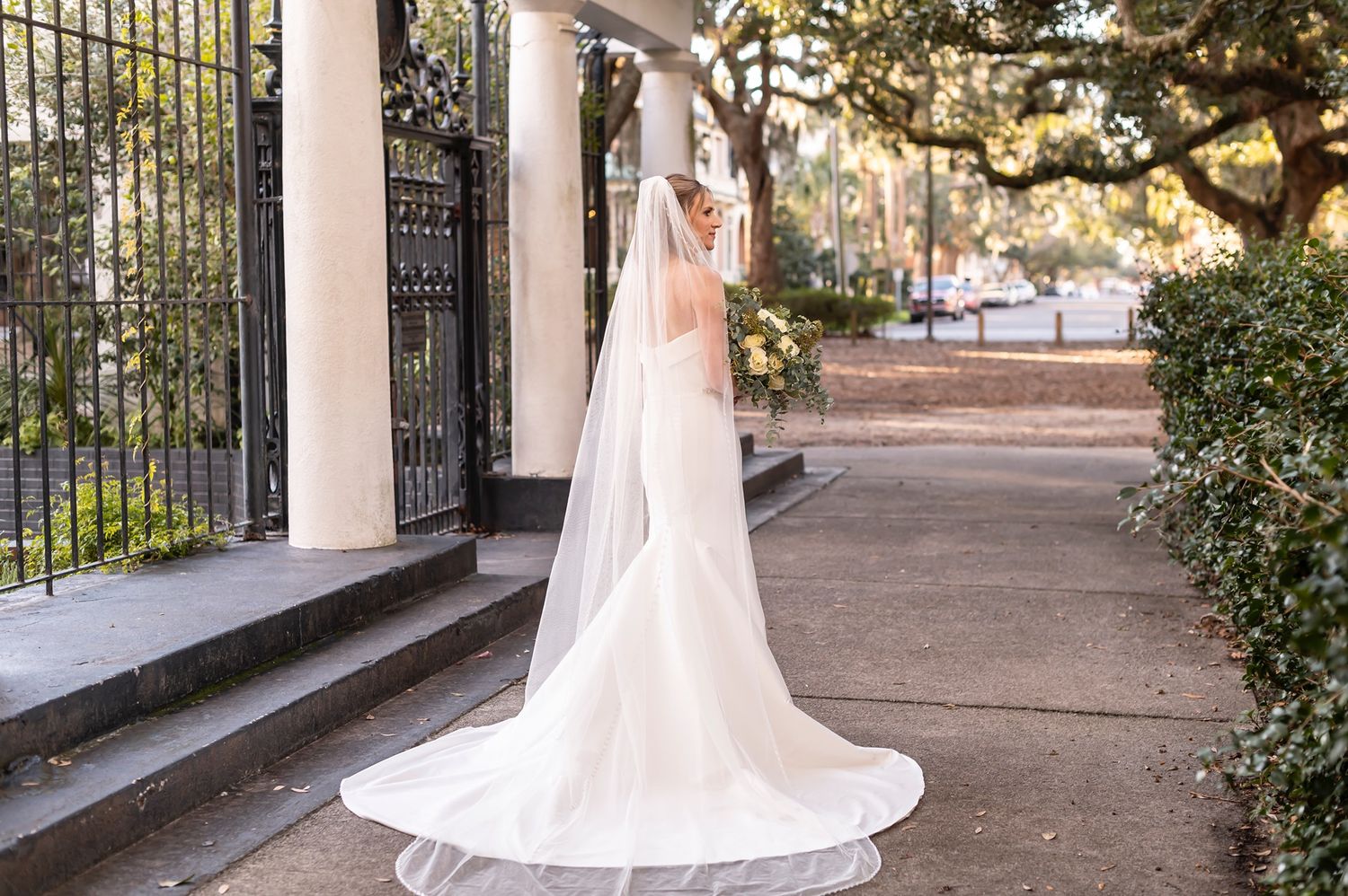 An elegant bridal photo session showcasing a flowing white dress train against classic architectural elements.