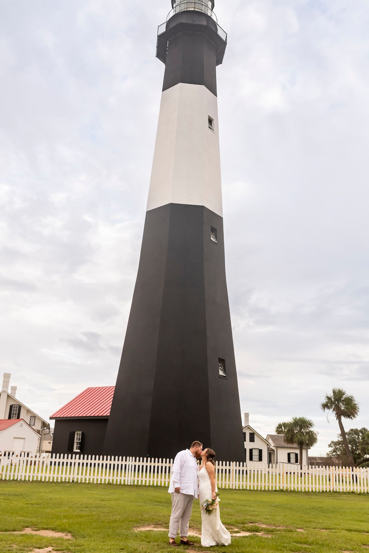 A sequence of romantic lighthouse photos shows a couple in white attire against a cloudy coastal backdrop and white fence.