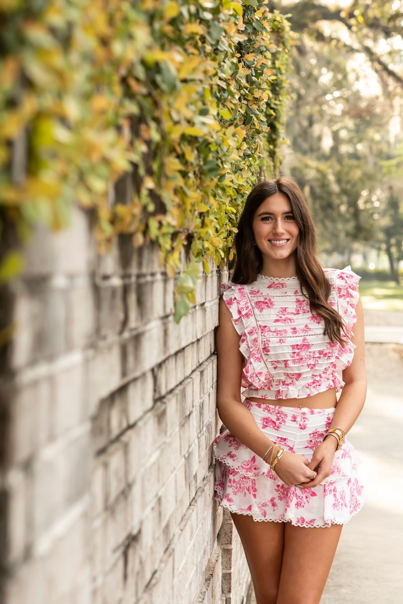 A stylish pink floral coordinated set captured in front of a stone wall with trailing vines.
