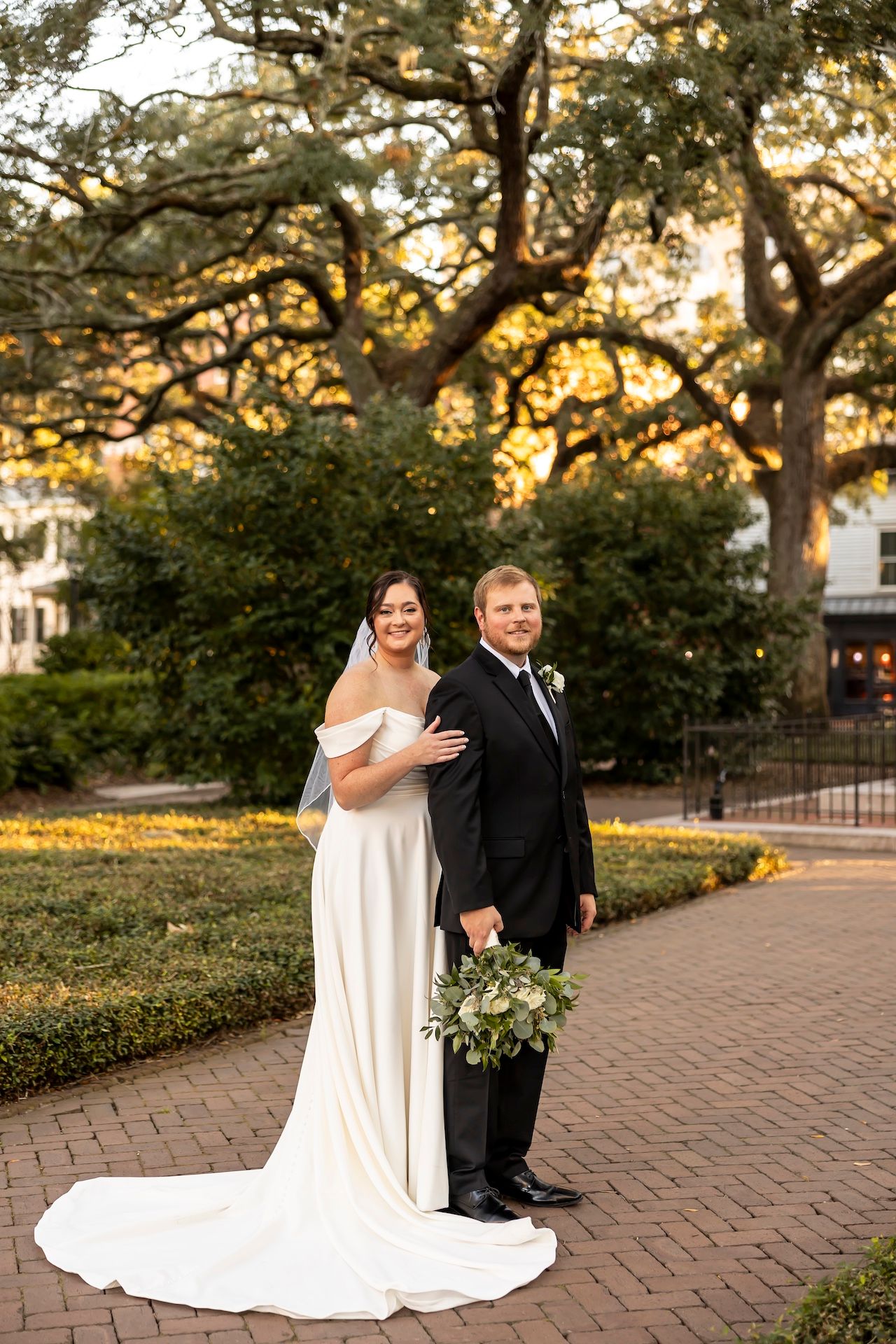 A romantic wedding photo series showing a couple in formal attire embracing on a brick path at sunset in a garden setting.