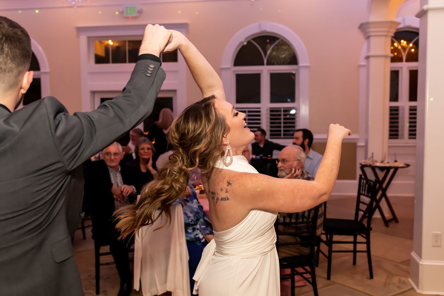 Couples dancing together at an elegant indoor venue with white walls and arched windows during an evening event.