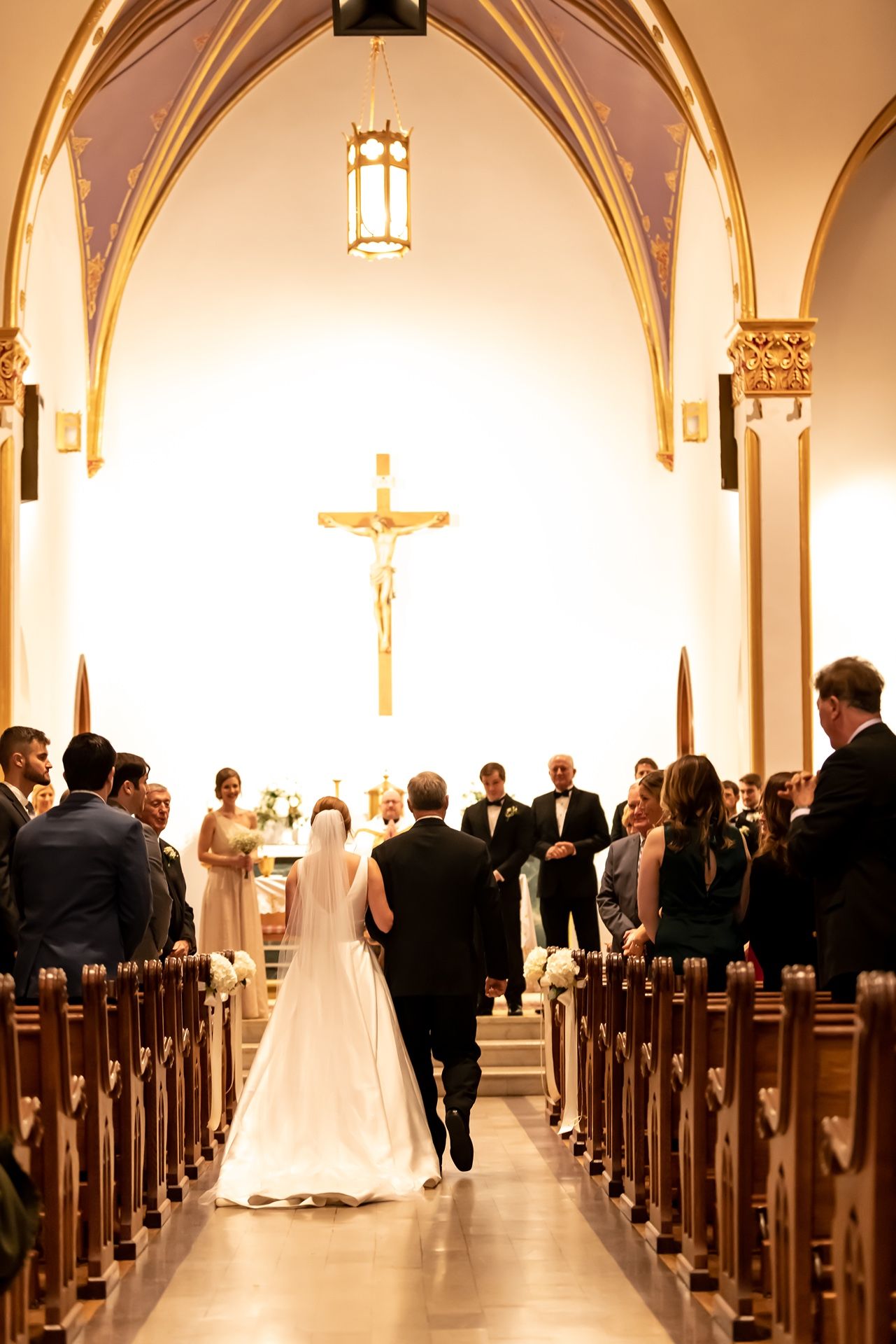 A traditional church wedding ceremony taking place in a chapel with vaulted ceilings and wooden pews.