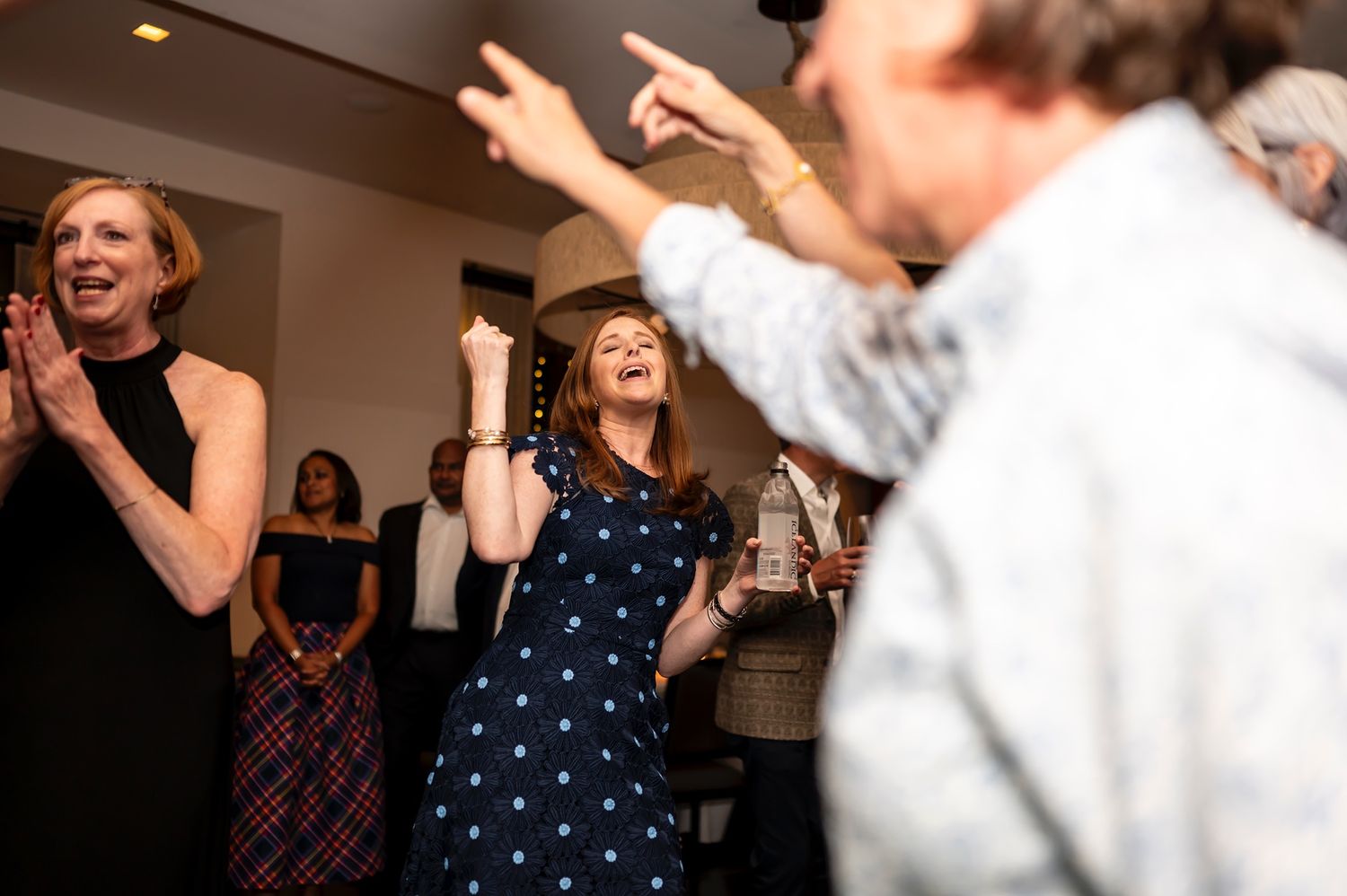 People dancing enthusiastically at a celebration party with joyful expressions and raised arms.