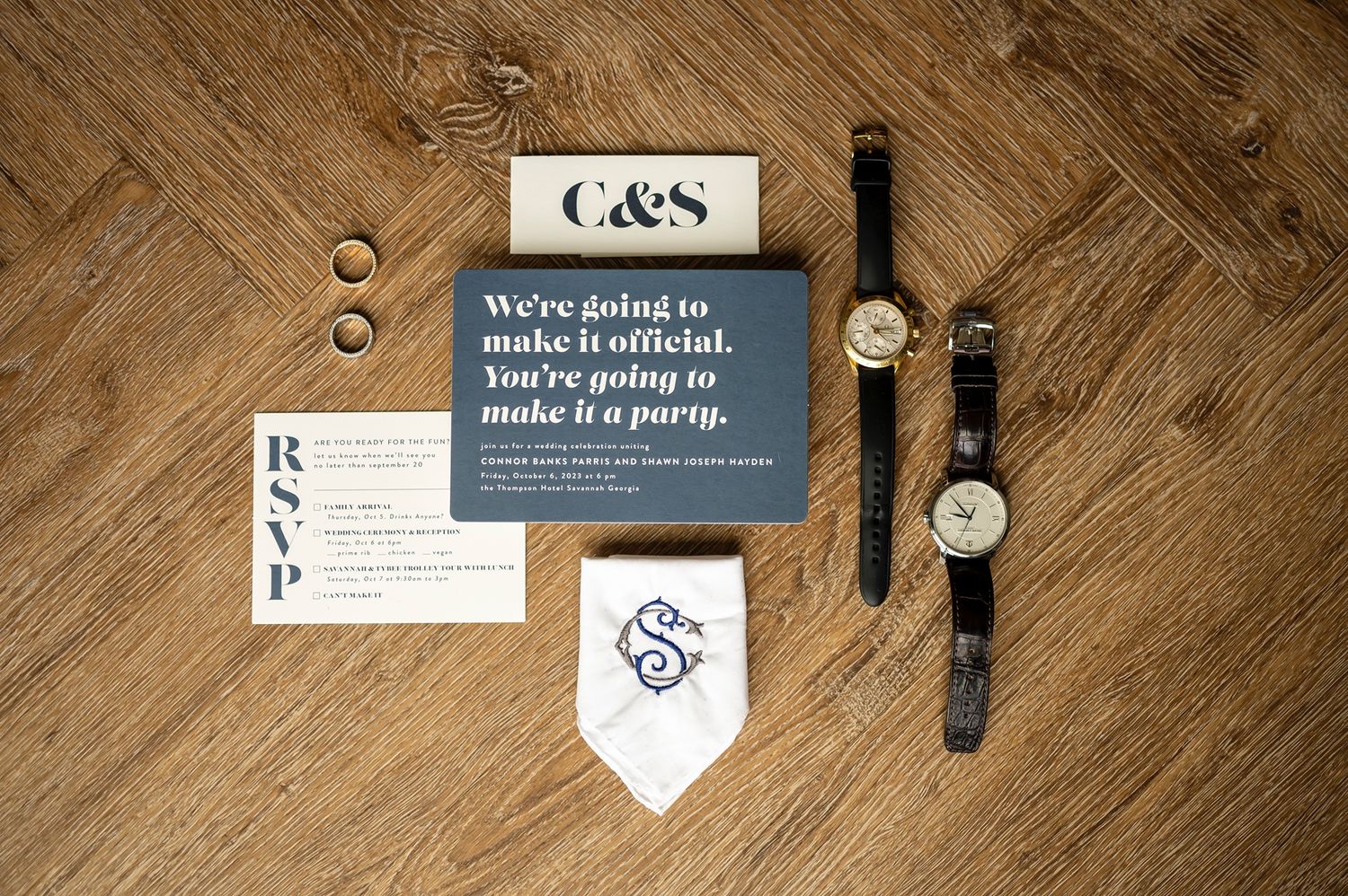 Business branding items including stationery, watches and printed materials arranged on a wooden floor surface.